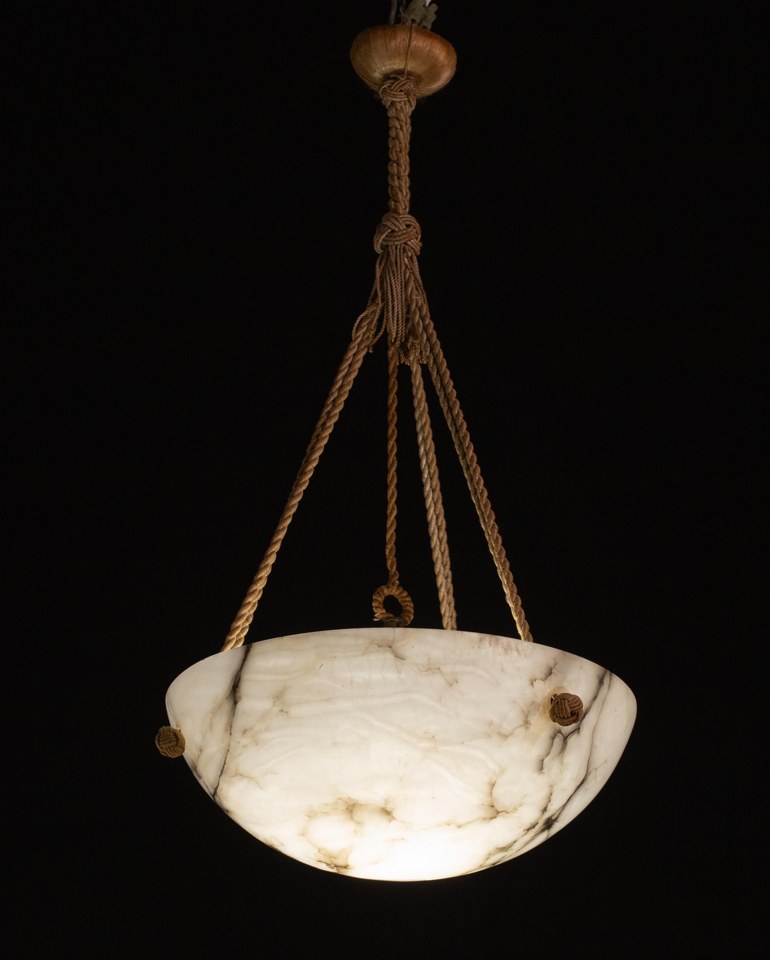Antique alabaster hanging lamp in Art Deco style, circa 1940s.
A single piece of alabaster, beautifully worked with shades and reflections of other colours when lit, suspended from three strands of rope, its original, can be changed to three chains