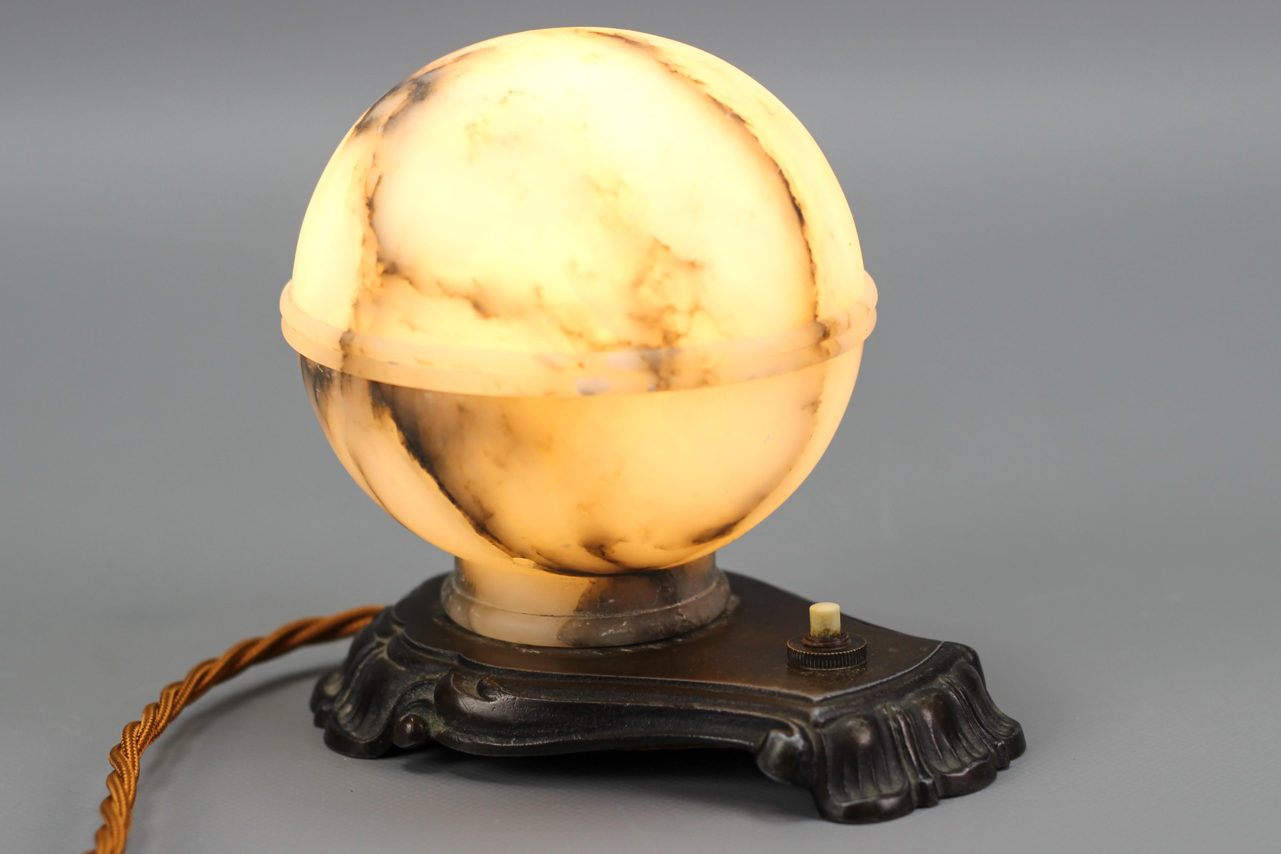 Art Deco White and Black Alabaster globe sphere night table lamp or mood lamp, France, circa the 1930s.
Absolutely adorable night table or mood lamp made that consists of a round lampshade made of two parts of white alabaster with black and dark