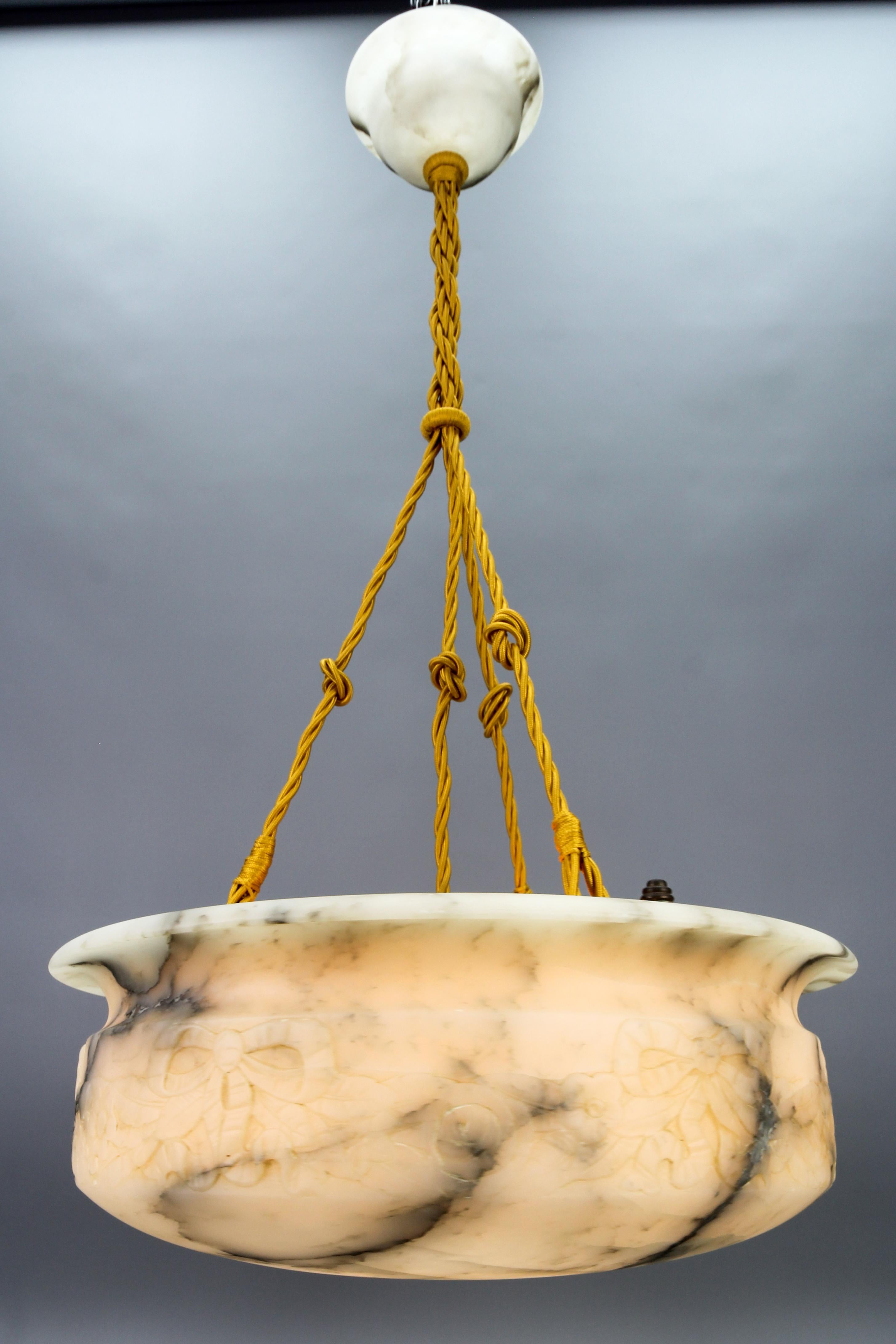 Art Deco White and Black Alabaster Pendant Light Fixture with Carved Flowers 
Gorgeous and large alabaster pendant ceiling light fixture from circa the 1930s. Beautifully veined and masterfully carved one-piece white alabaster bowl suspended by