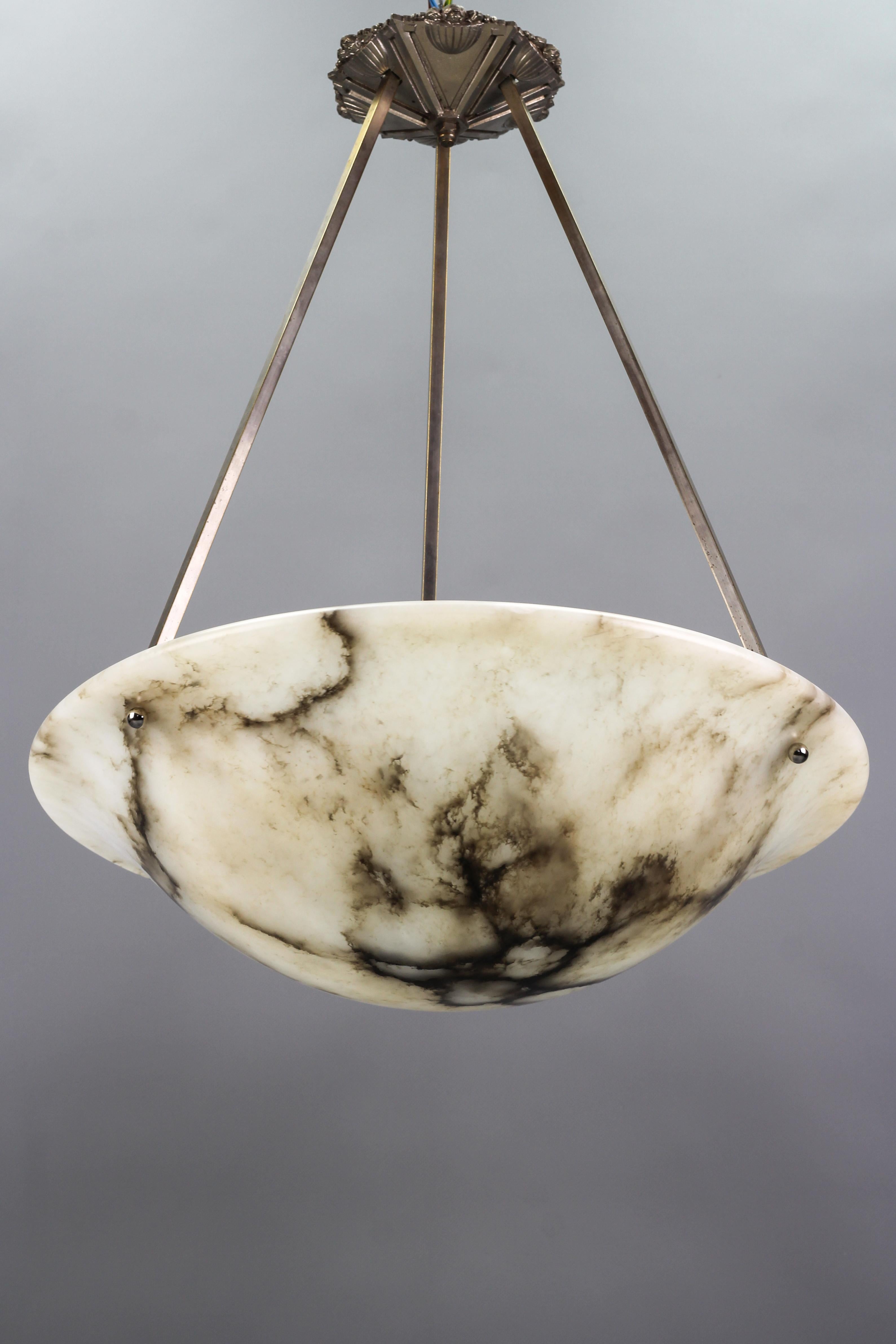 Gorgeous and large Art Deco period alabaster pendant ceiling light fixture. France, 1920s. Beautifully veined and masterfully carved one-piece white alabaster bowl suspended by chromed brass frame with three branches and an ornate Art Deco style