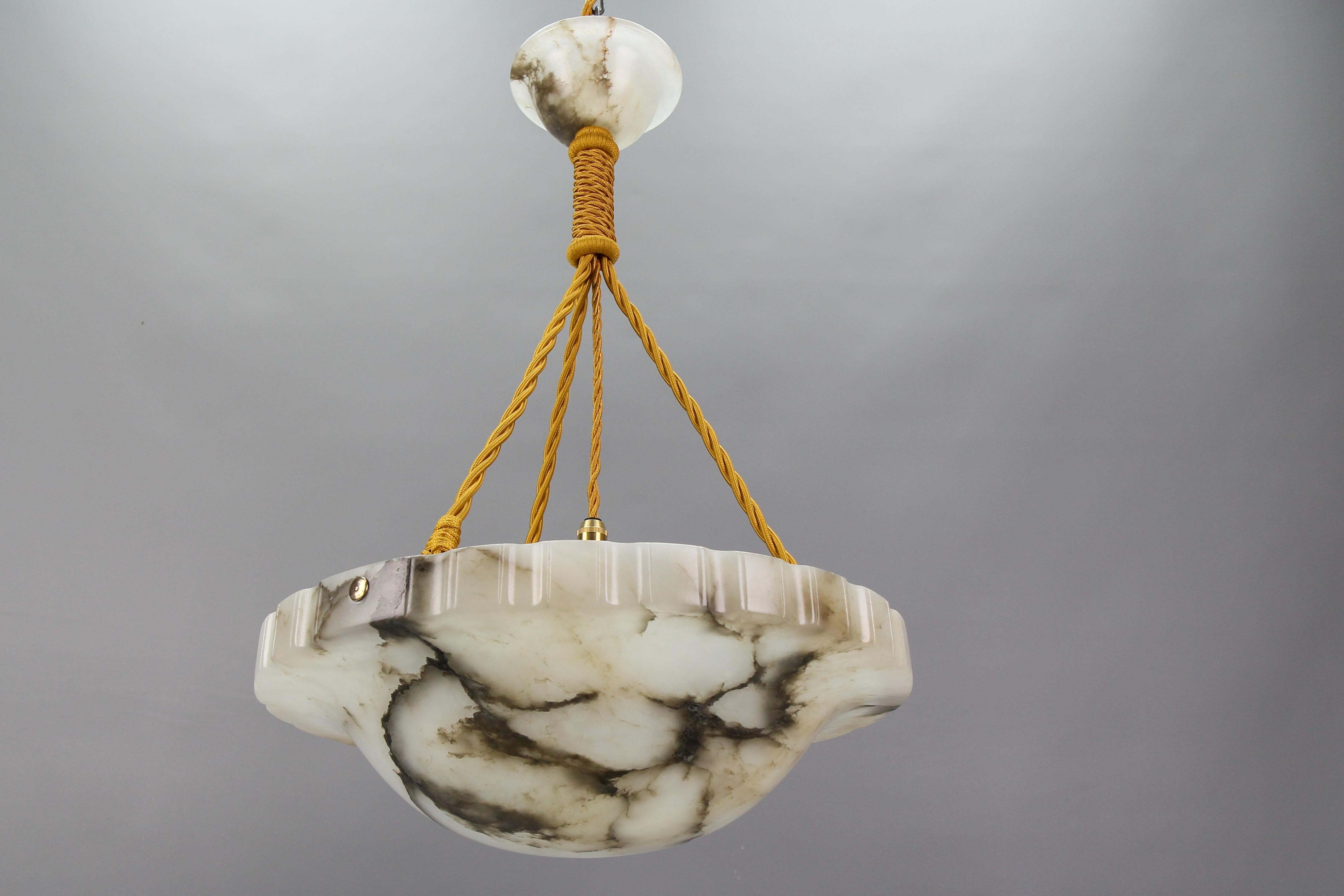 Art Deco white and grey alabaster pendant light fixture with black veines, France, circa the 1920s.
An impressive and wonderfully shaped alabaster pendant ceiling light fixture from circa the 1920s. Beautifully veined and masterfully carved white