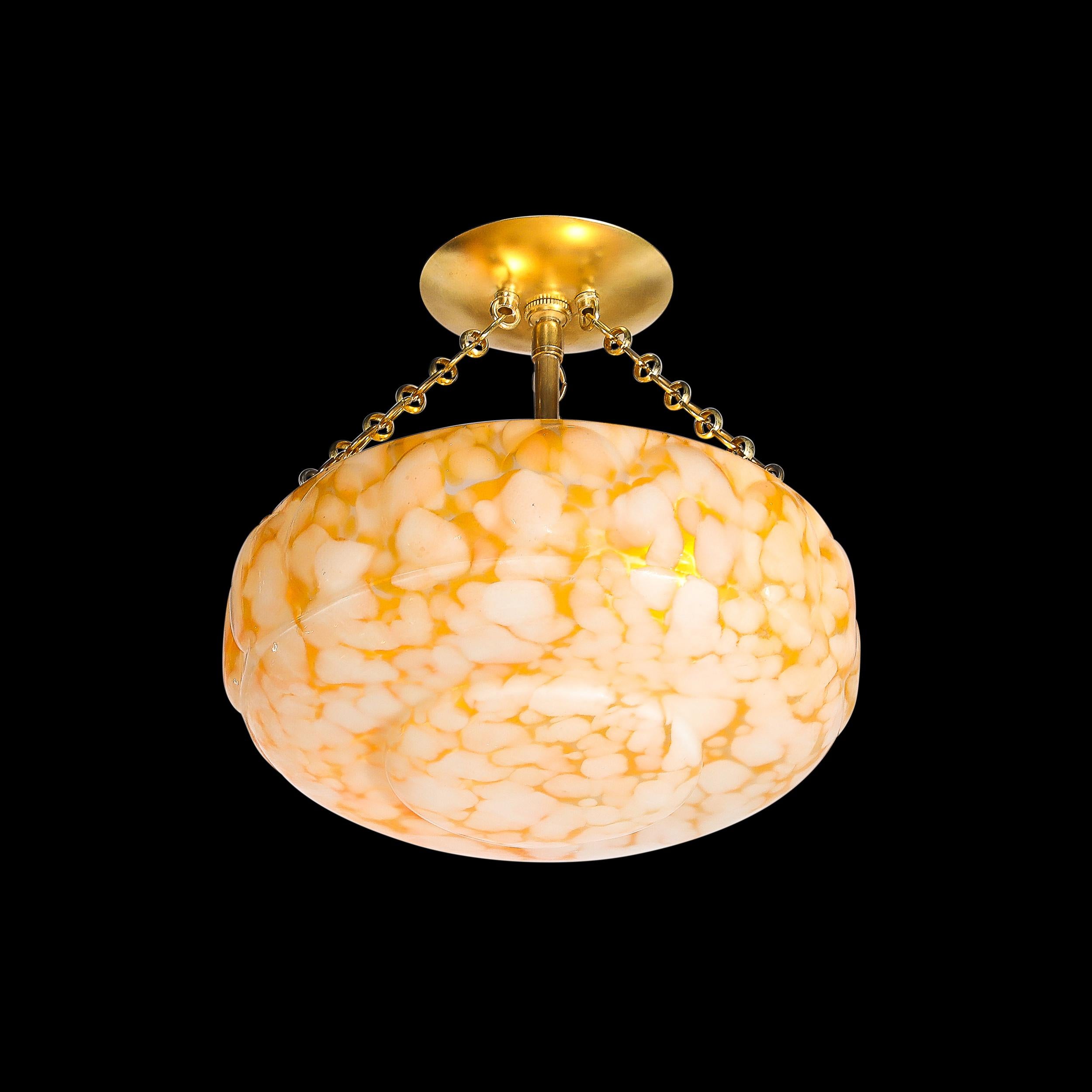 This well formed and materially unique Art Deco White and Orange Glass Pendant Chandelier W/Brass Fittings originates from France, Circa 1930. Featuring a shade formed in a single piece of molded glass with a patchwork of warm yellow orange and off