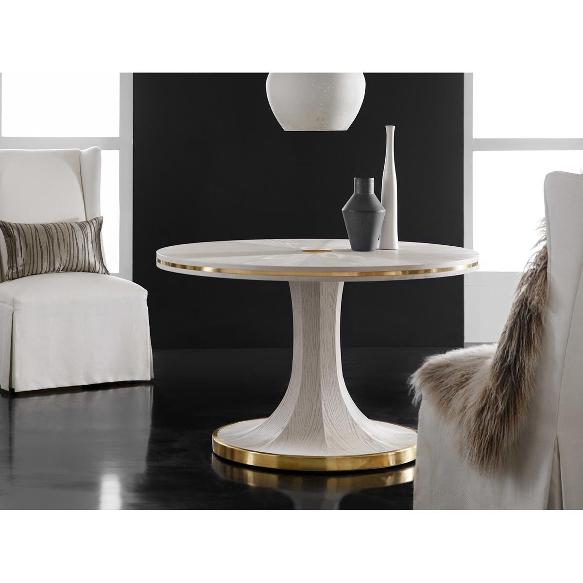 Art Deco White Center Table with white wash oak veneer. A rayed top centered by an antiqued brass round applique, with brass inlaid trim and raised on an octagonal pedestal with a round brass mounted base.

Dimensions: 48