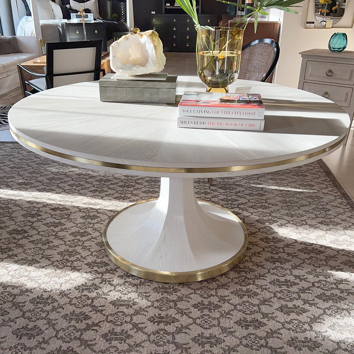 Introducing the Art Deco White Dining Table. With its whitewash oak veneer and rayed top centered by an antiqued brass round applique.

The top with brass inlaid trim is raised on a tapered octagonal pedestal with a round brass mounted base that