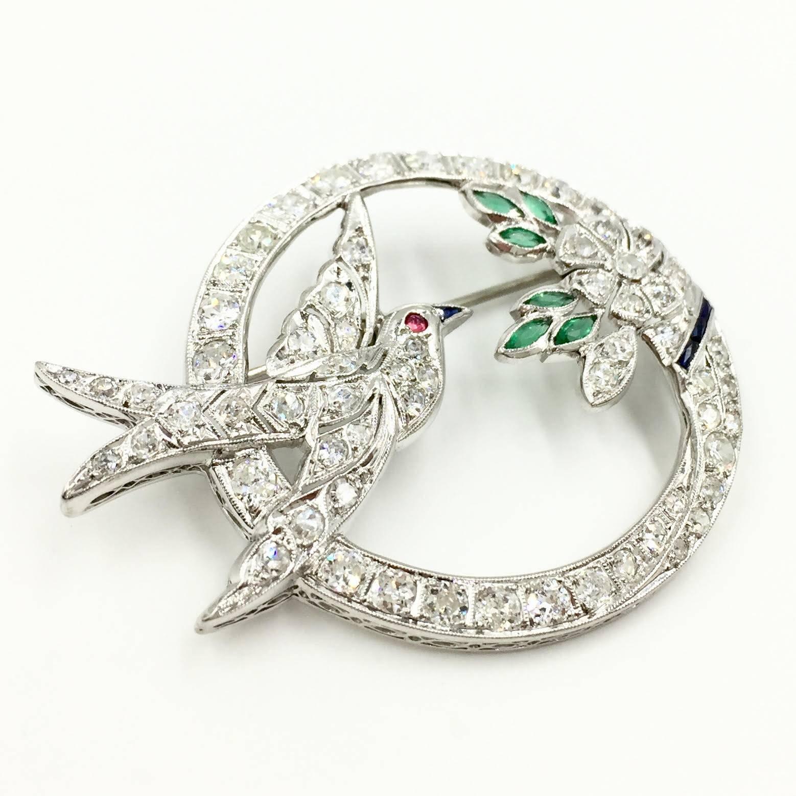 Circa 1950's, this beautiful Art Deco Style detailed brooch is adorned with diamonds, emeralds, sapphires and a ruby. Perfect for a jewelry lover. This interesting piece can easily be converted to a pendant.