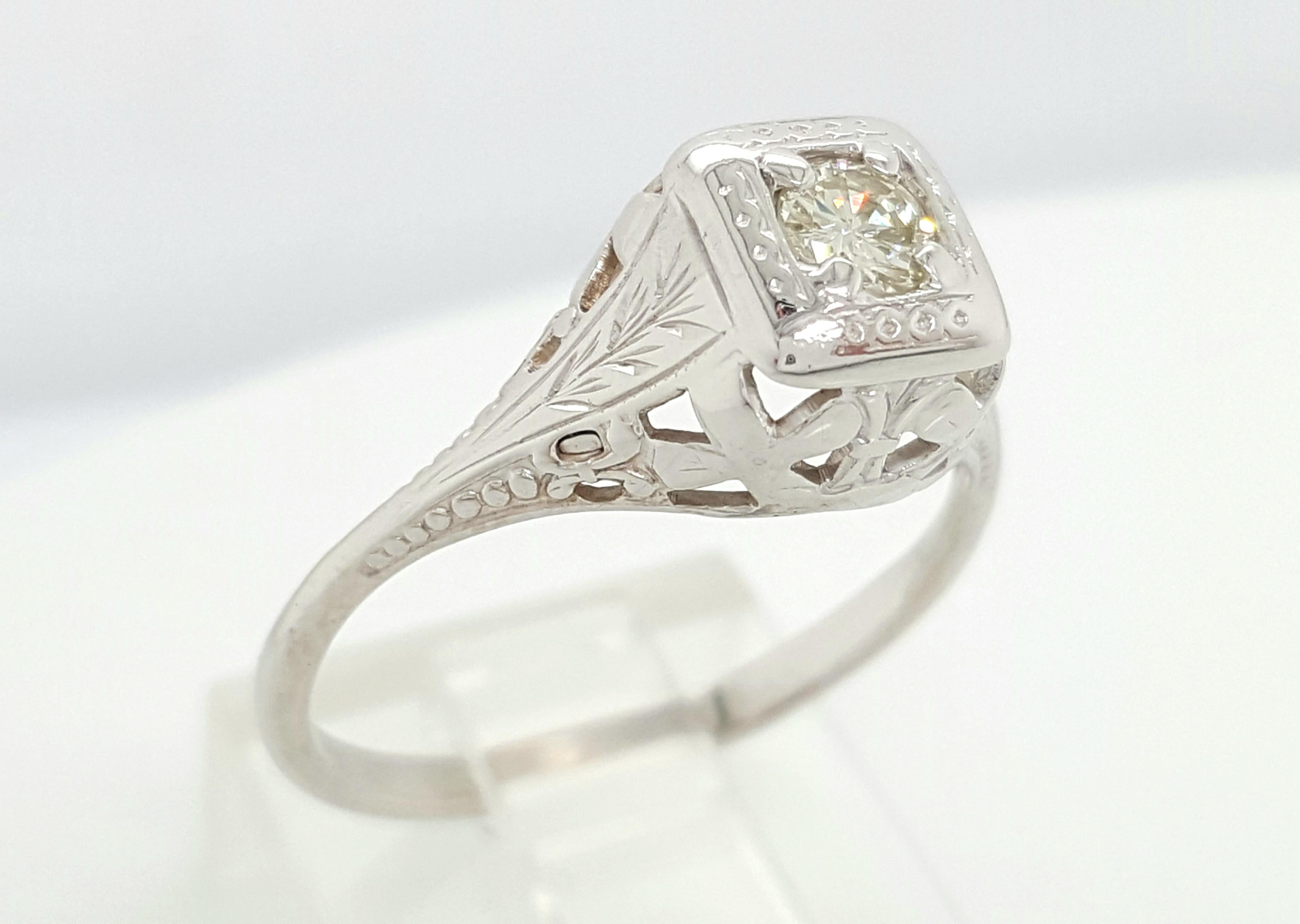 This Art Deco solitaire is a fine example of a filigree solitaire engagement ring crafted in 14 karat white gold. The Round Cut cut diamond is held high in four prongs showcasing the solitaire from all sides! Flowing down from the sparkling center