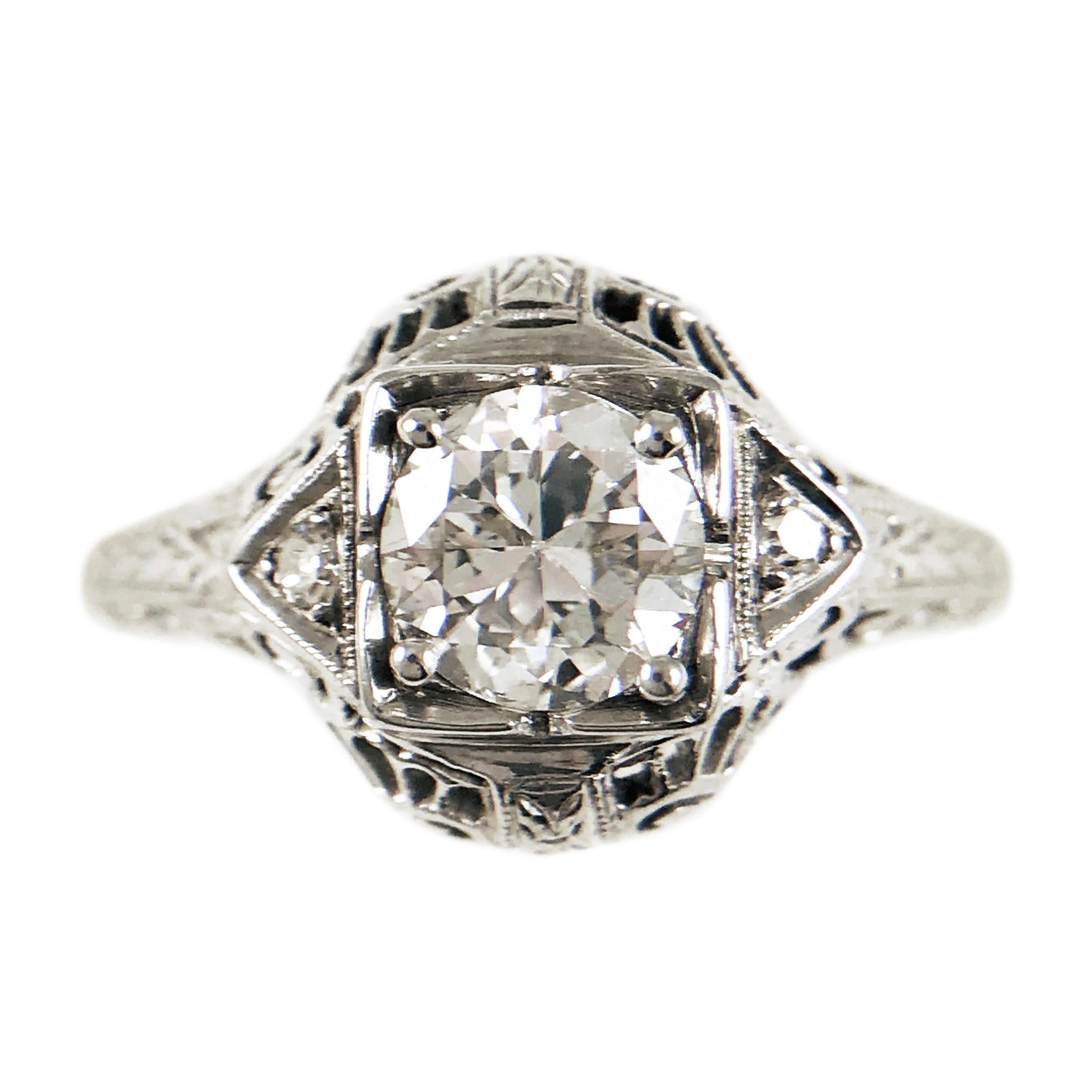 Art Deco 14 Karat White Gold Three Diamond Ring. Gorgeous filigree detail on this period-correct ring. The center round brilliant-cut diamond serves as the focal point as the two smaller single-cut diamonds accent each side. The total carat weight