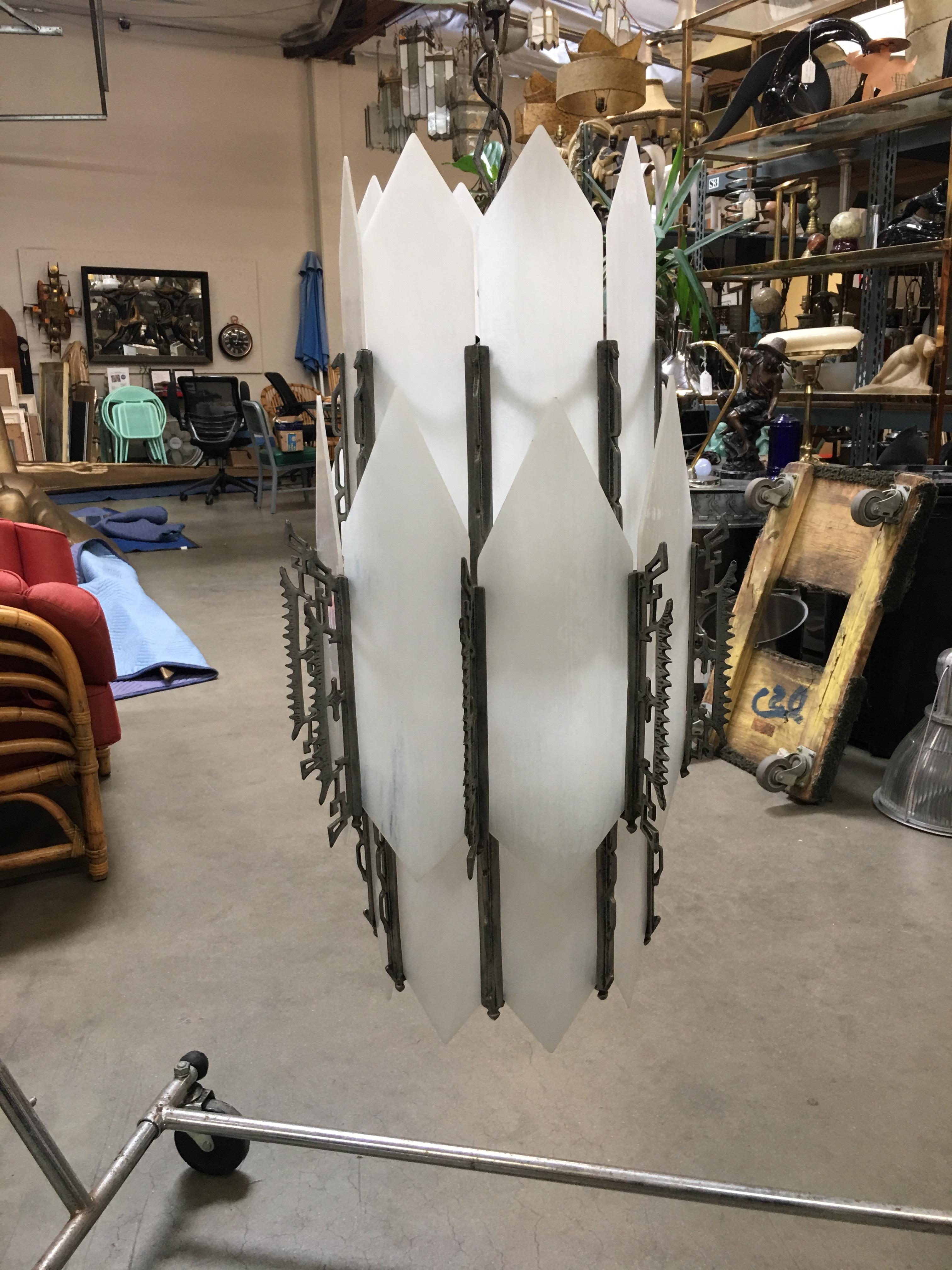 Geometric Art Deco chandelier with five hanging lights in a light-up slat glass center. The piece features scrolling details throughout.