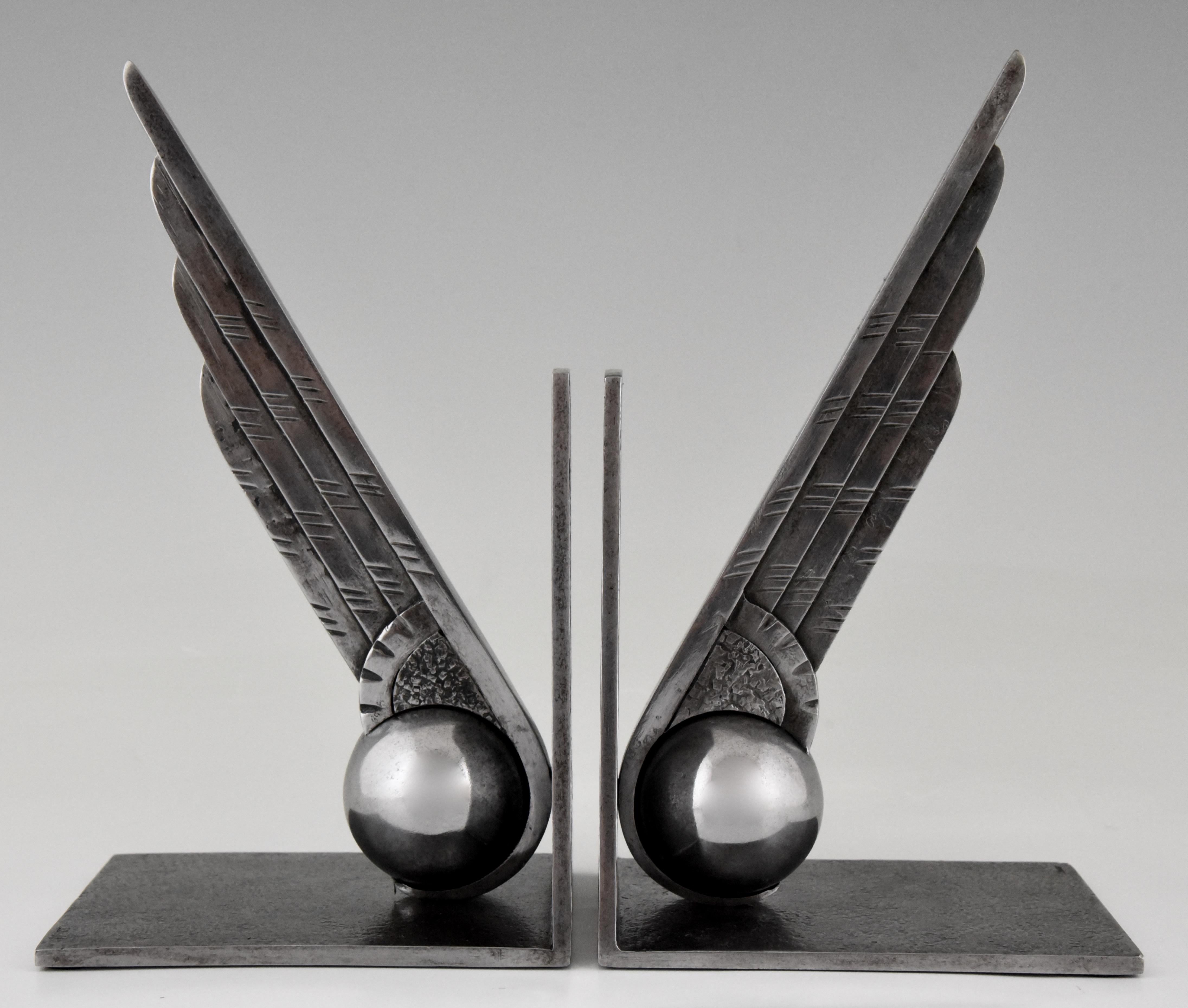 Stylish pair of wrought and cast iron ball and wing bookends on an angular support mounted on a rectangular base by Edgar Brandt, France 1930.

“Edgar Brandt master of Art Deco ironwork” by Joan Kahr. These bookends were designed to commemorate