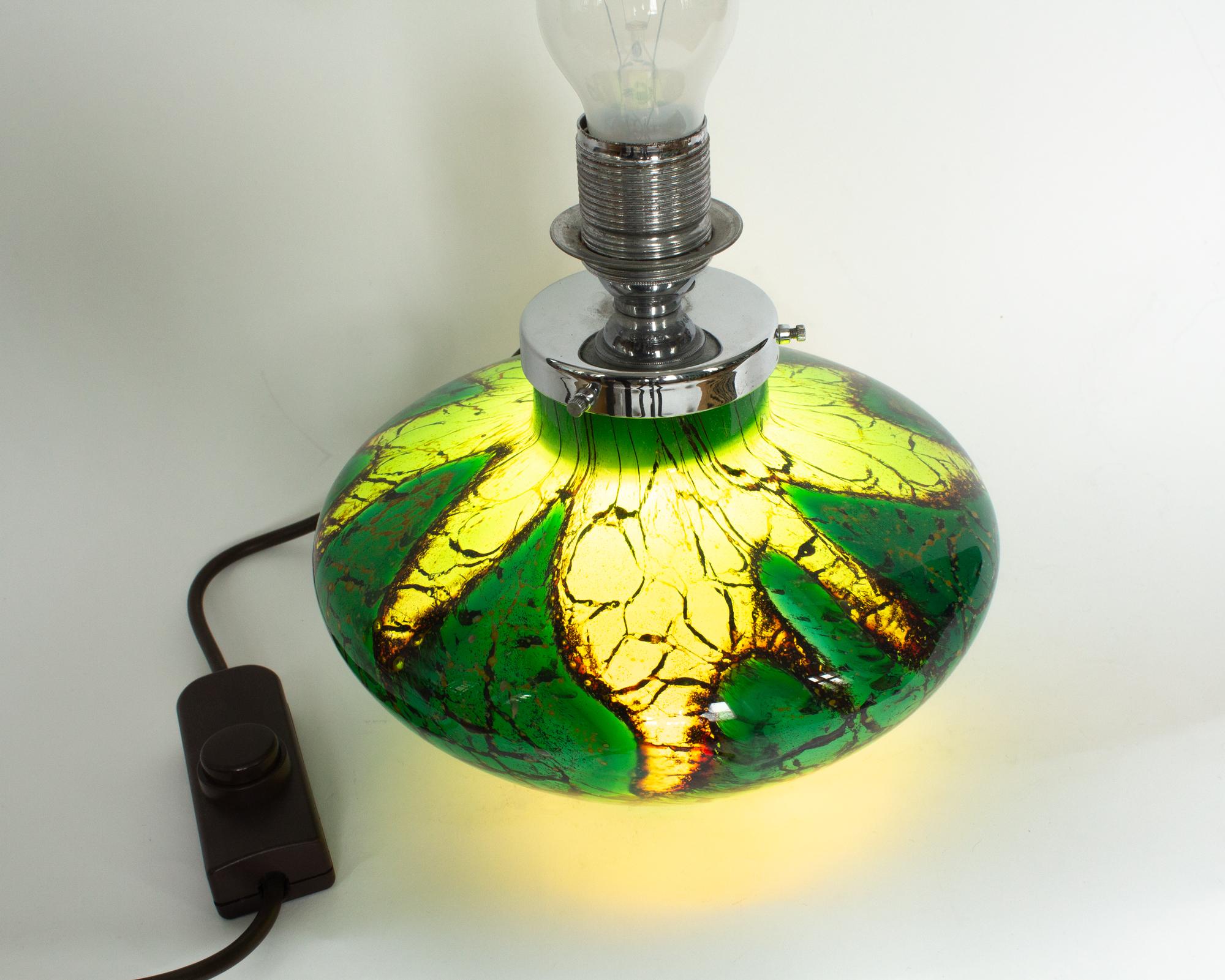 Lampe de table Art Déco WMF Ikora en verre d'art vert, noir et or. Le verre présente des bulles, ce qui donne à la base un aspect fantastique lorsqu'elle est éclairée. La lampe en verre est colorée en vert, or et noir. Il a l'ancien cordon et