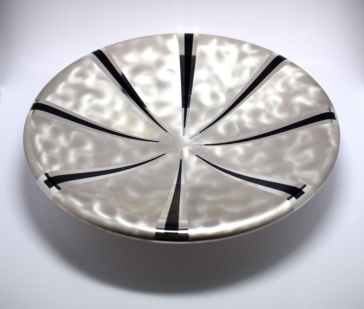 Magnifique bol Art Déco en métal argenté de WMF Ikora. Une coupe peu profonde décorée à l'intérieur de lignes radiales noires qui s'écartent du centre vers l'extérieur. En dessous se trouvent trois pieds circulaires en forme de boule.
Marqué avec