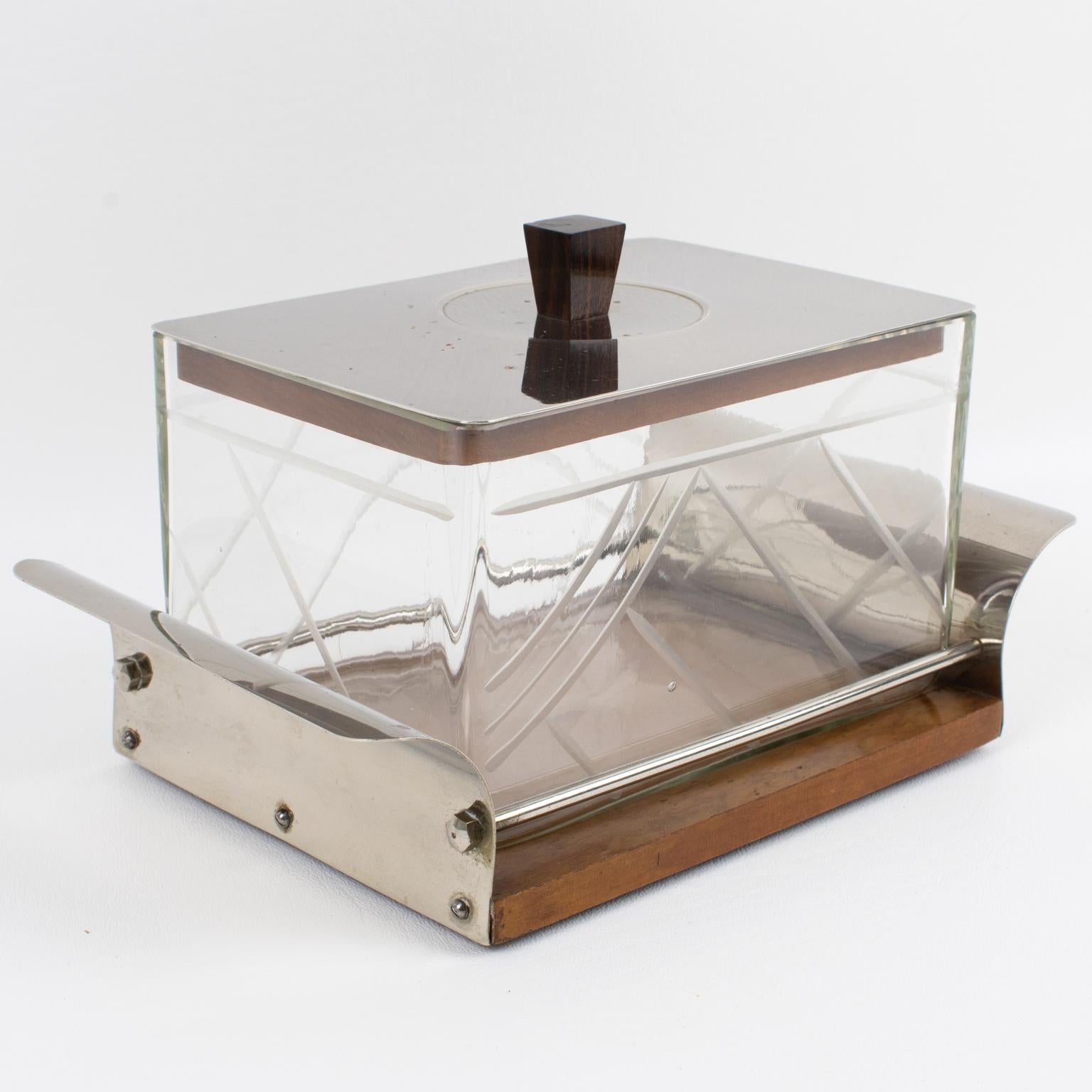 Esta refinada caja decorativa Art Decó para galletas o caramelos, con un cuenco para servir, se fabricó en Francia en la década de 1930. Su diseño modernista cuenta con una base de soporte de metal cromado y madera con asas en relieve. El cuenco de