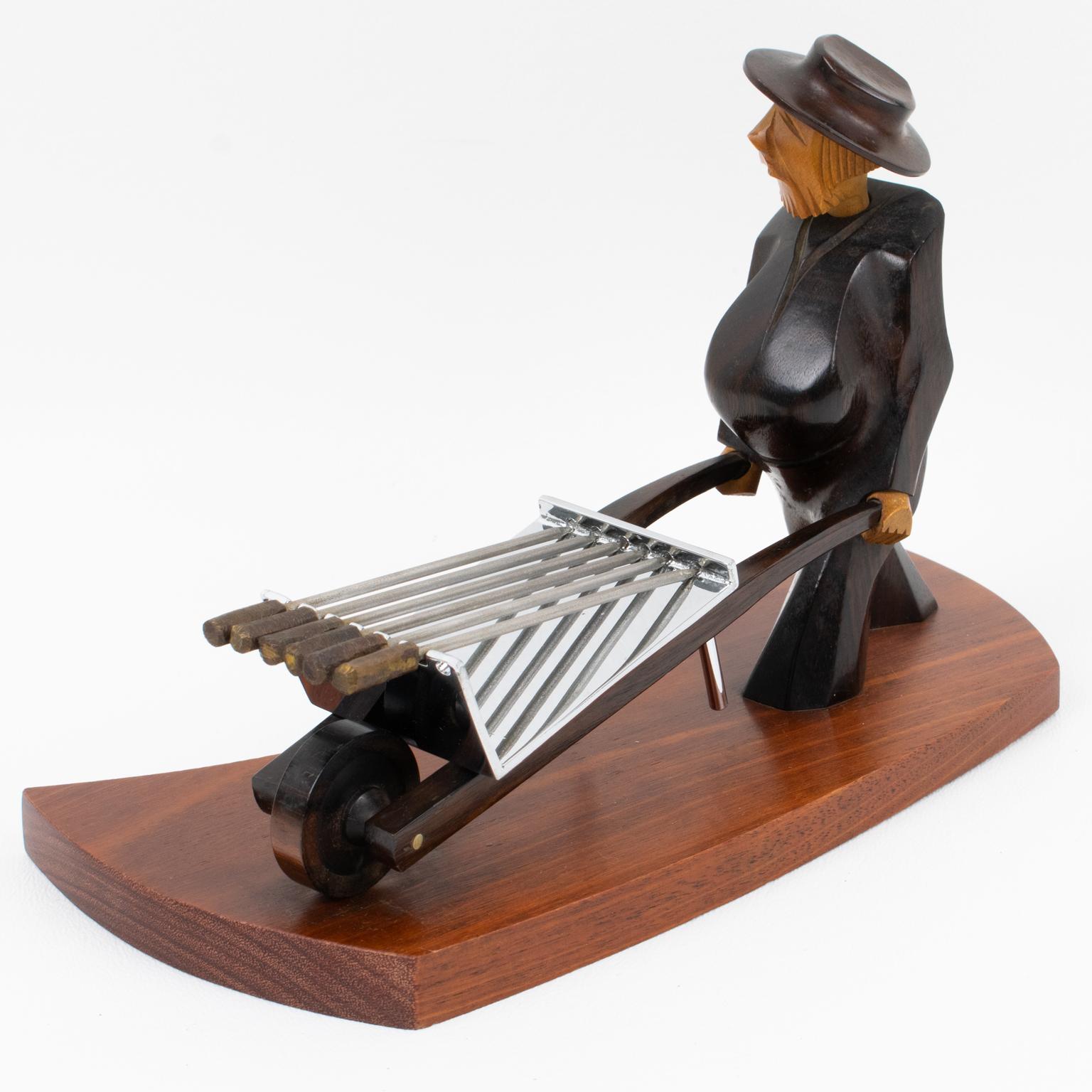 This stunning Art Deco barware bar set was designed and crafted in the 1930s in France. The cocktail picks accessory features a man pushing a wheelbarrow with picks. The man character is hand-carved with tropical woods. The wheelbarrow is built with