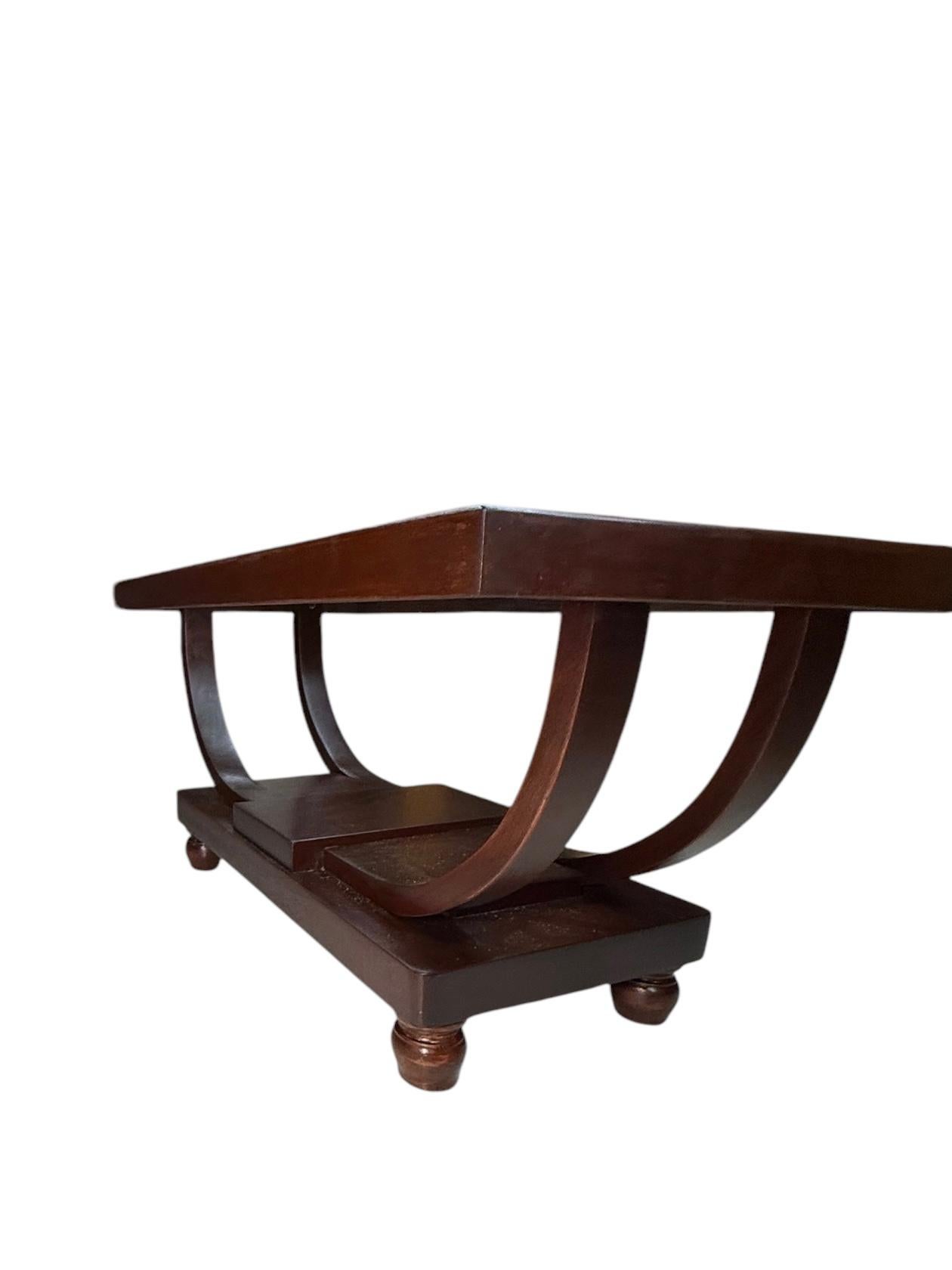 Il s'agit d'une petite table basse Art Déco en bois et verre. Il représente un plateau rectangulaire en verre transparent encadré de bois brun foncé fixé à deux pieds en bois parallèles en forme de demi-lune fixés à une base rectangulaire en bois