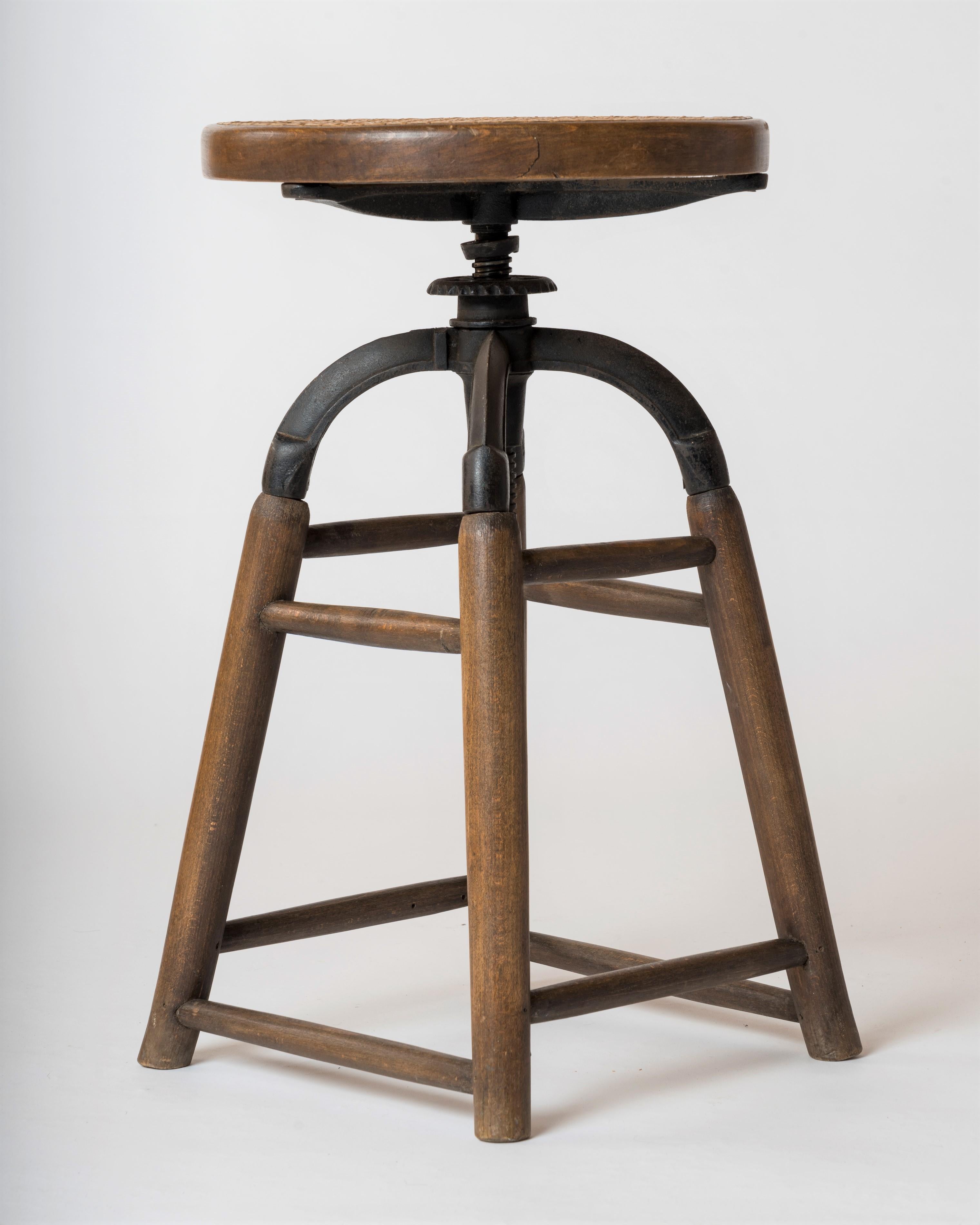 Signed elegant and sturdy four legged adjsutable stool by Thonet. The base structure is made of wooden legs inserted into a cast iron structure. The seat itself can be adjusted for heitgh thanks to a screw mecanism. 
Minimum height is 58cm.
In