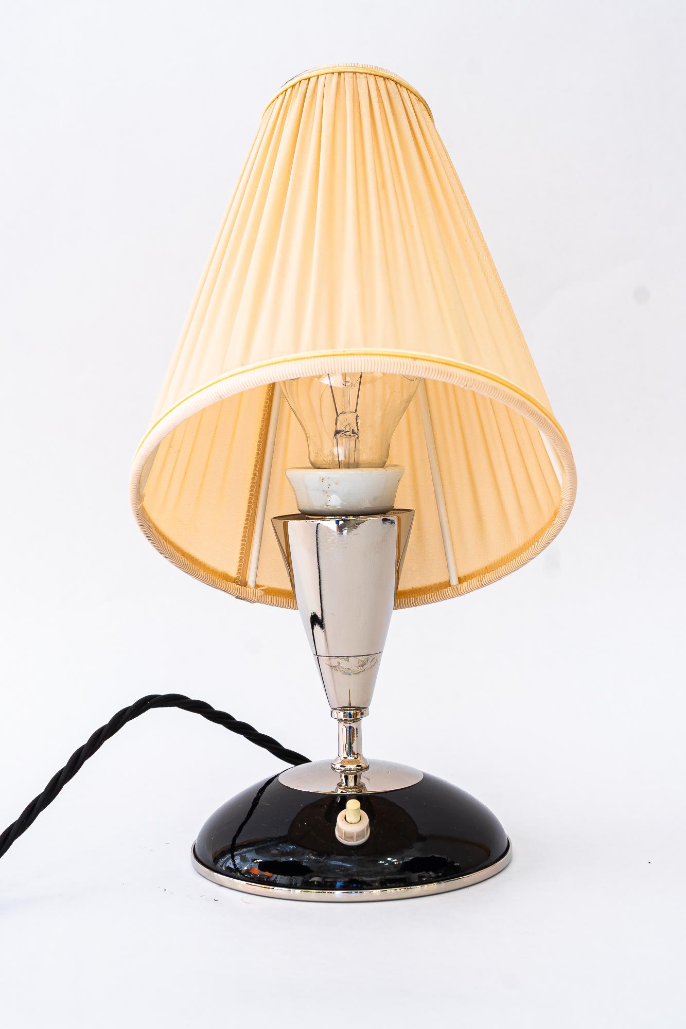 Lampe de table Art Déco en bois avec abat-jour en métal nickelé et tissu vienne années 1920
Métal nickelé 
Les stores en tissu sont remplacés (neufs).