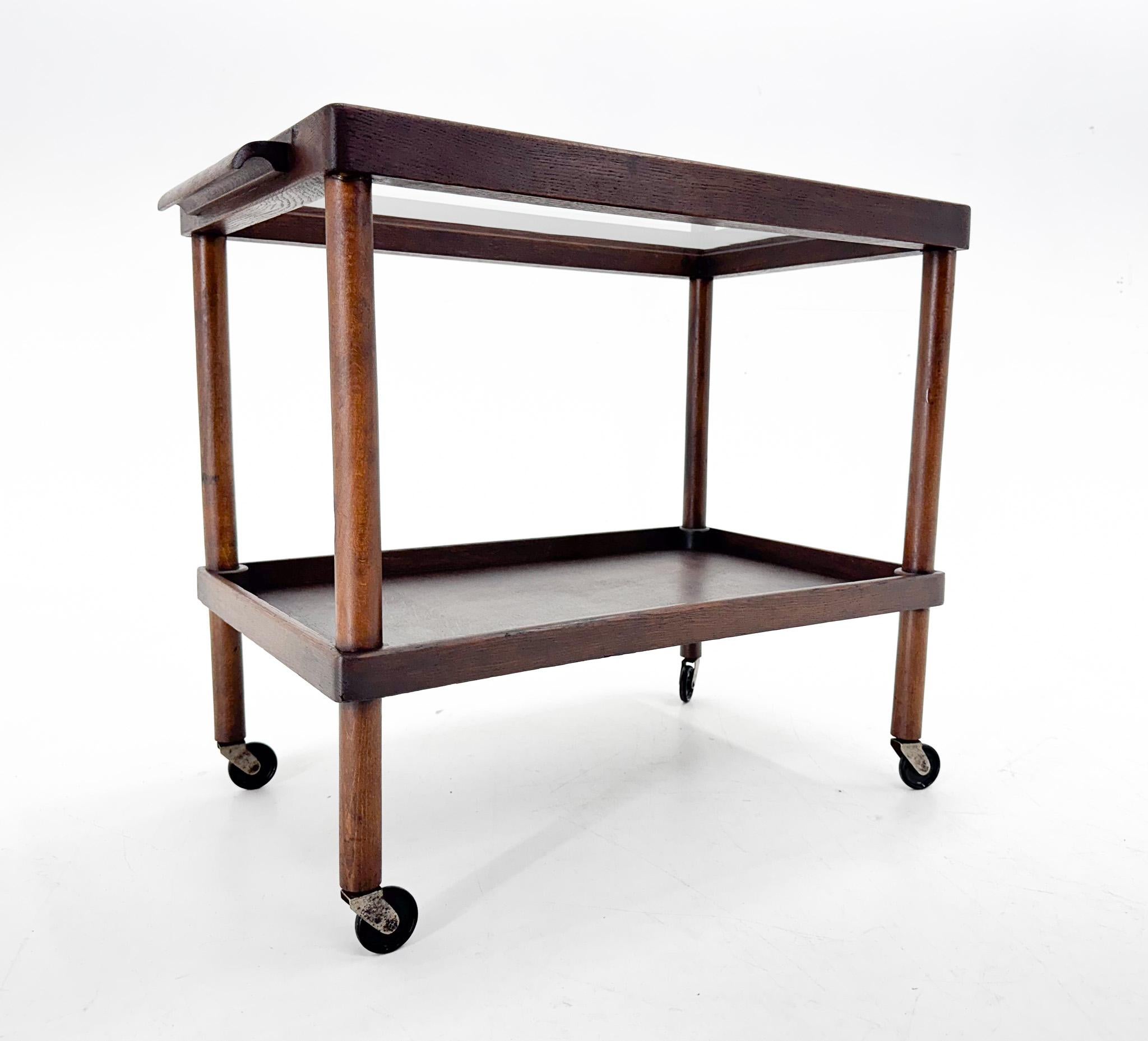 Elegant wooden bar cart / trolley on wheels with one handle and glass top. The glass is original and so has some slight signs of use.