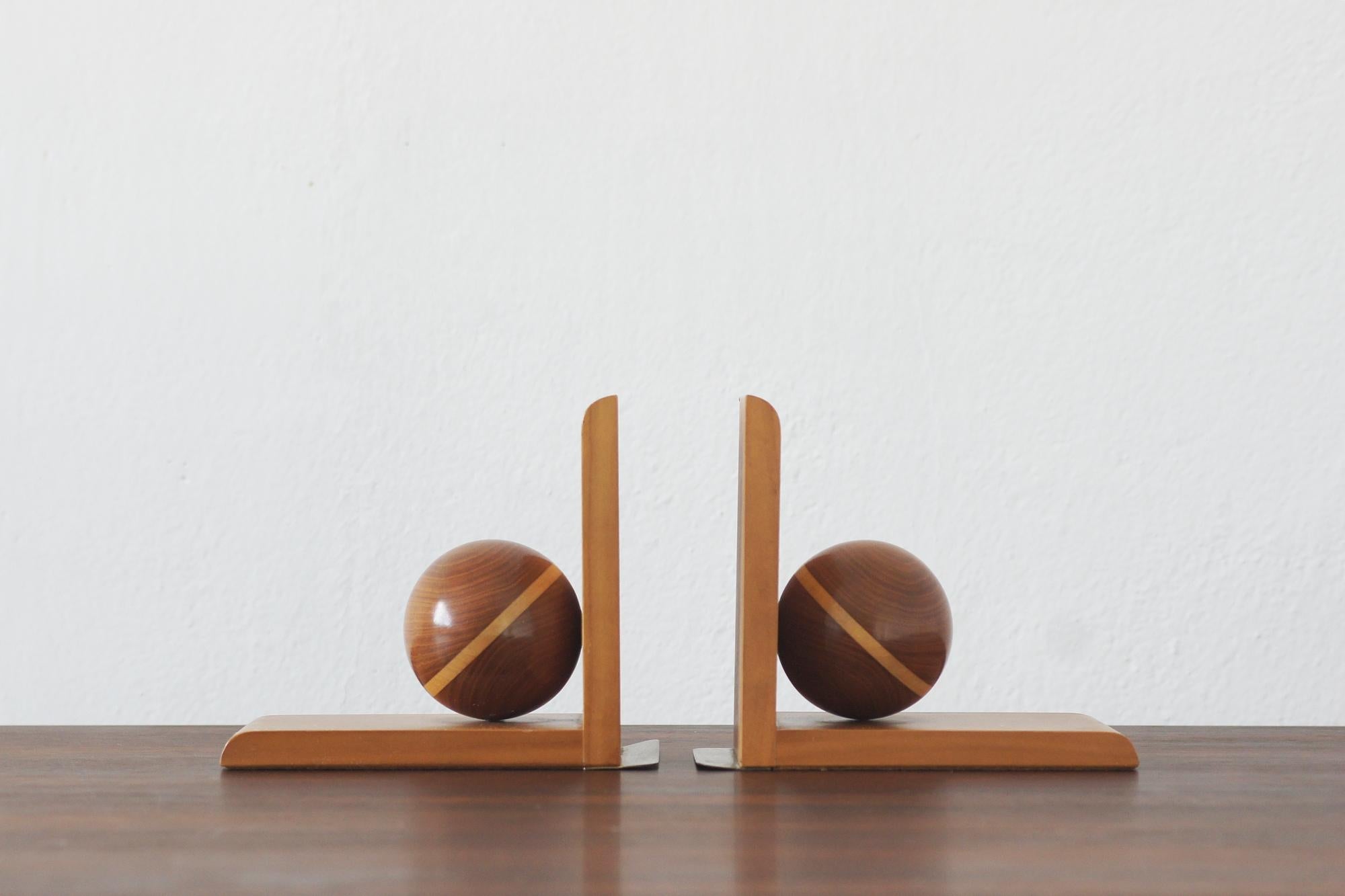 Una squisita coppia di reggilibri in stile Art Déco, realizzati in legno massiccio, presenta un audace design geometrico con scultorei accenti sferici. Le ricche venature del legno ne accentuano il calore e l'eleganza, rendendoli un'aggiunta senza