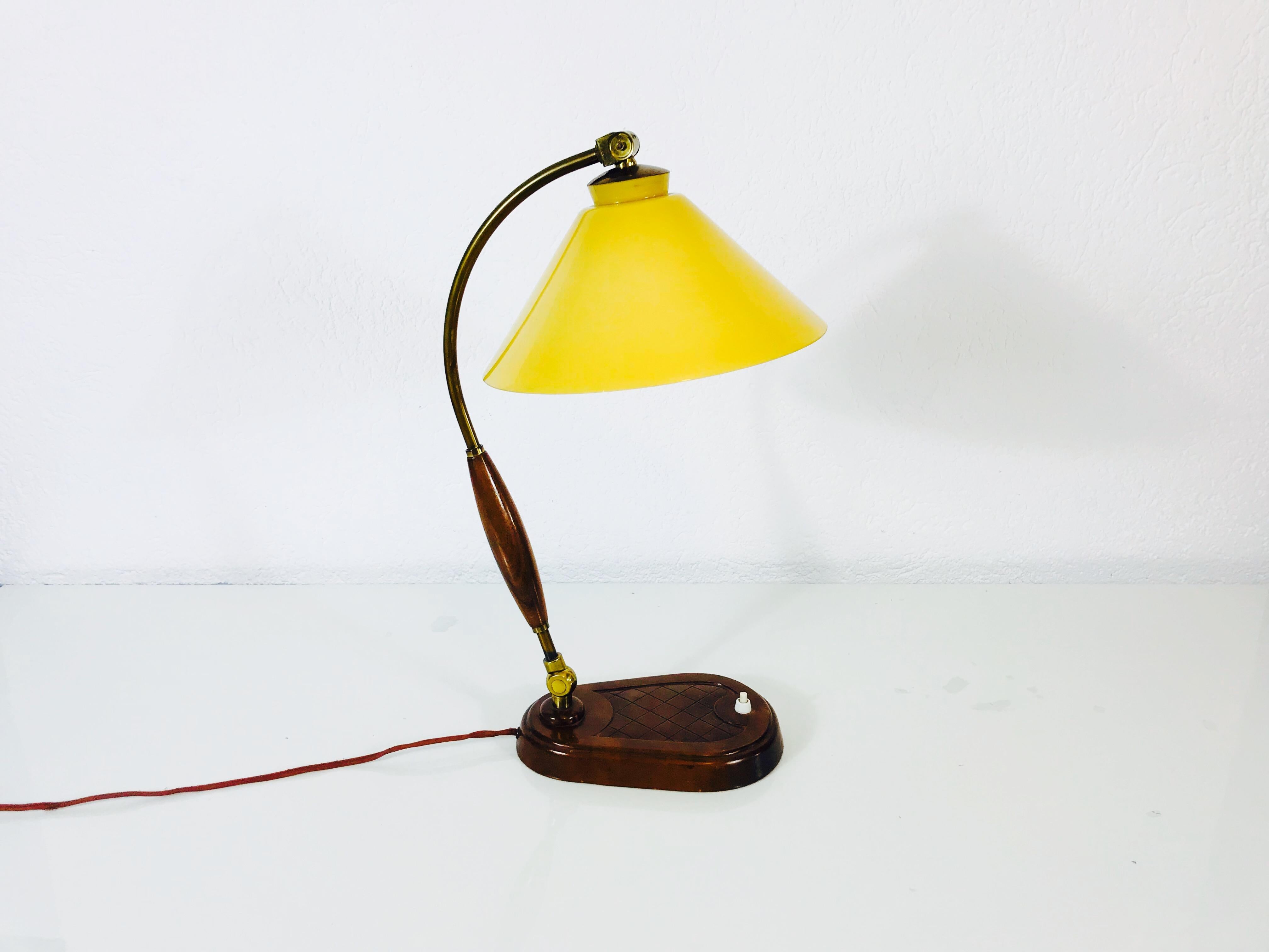 Une belle grande lampe de table fabriquée dans les années 1940. Il a un beau corps en bois avec des ornements en laiton. L'abat-jour en verre est de couleur jaune. La lampe de table a un beau design italien.

Le luminaire nécessite une ampoule E27.