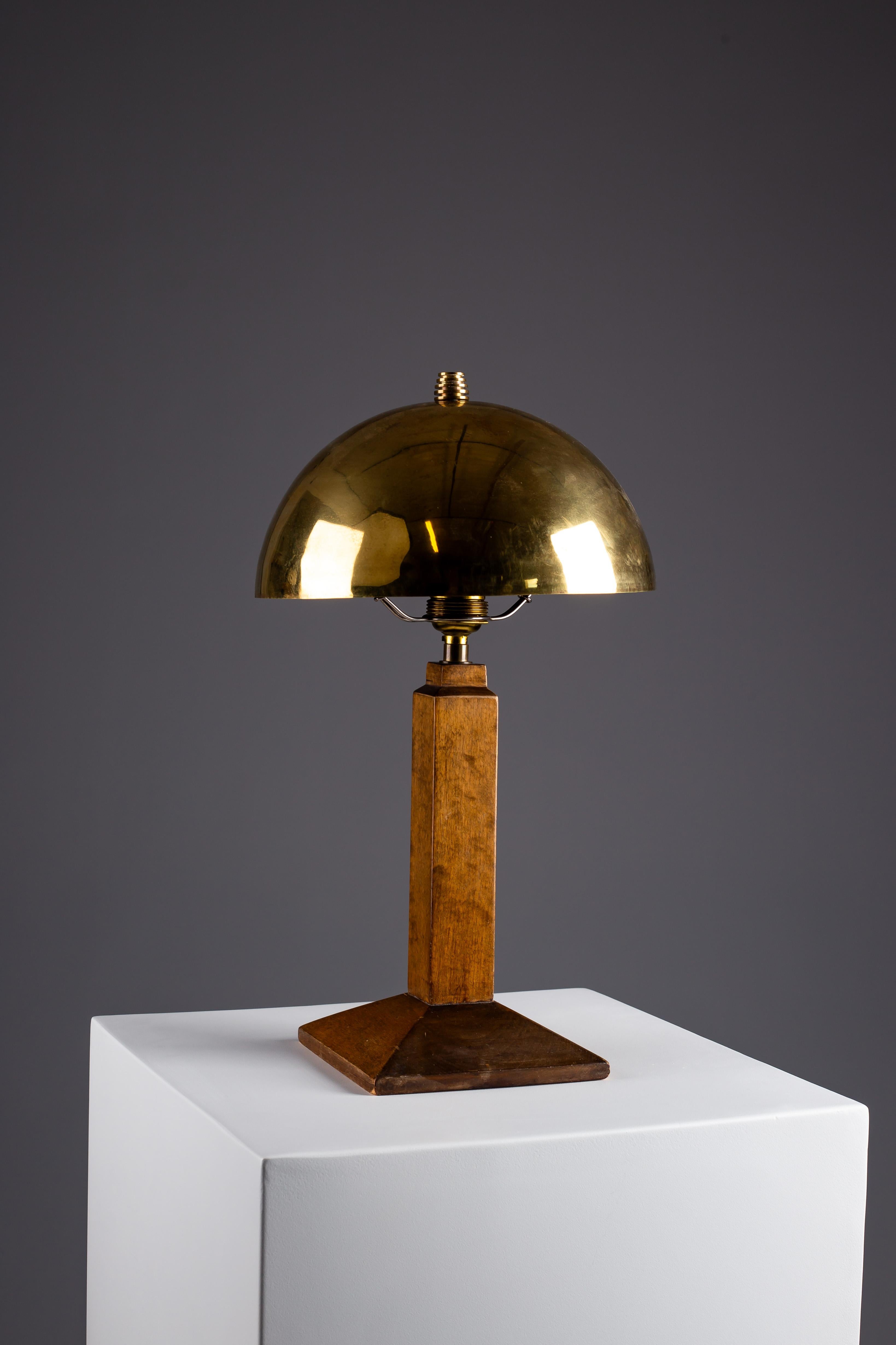 Discover elegance with this Art Deco wooden table lamp. An exquisite piece crafted by an anonymous designer, this lamp effortlessly blends form and function. Its rounded polished brass lamp shade adds a touch of vintage sophistication, while the