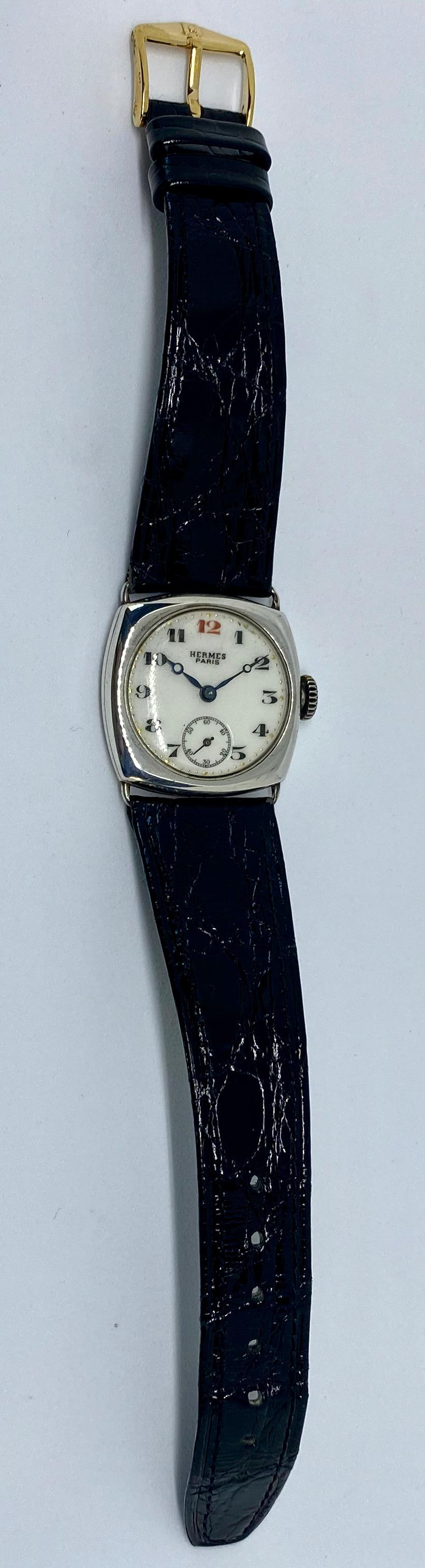 A vintage, entirely original, manual-wind wristwatch signed Hermes Paris.

Featuring a round, white porcelain face in a squared sterling silver case, with Breguet numerals in black (red at 12:00), Breguet (