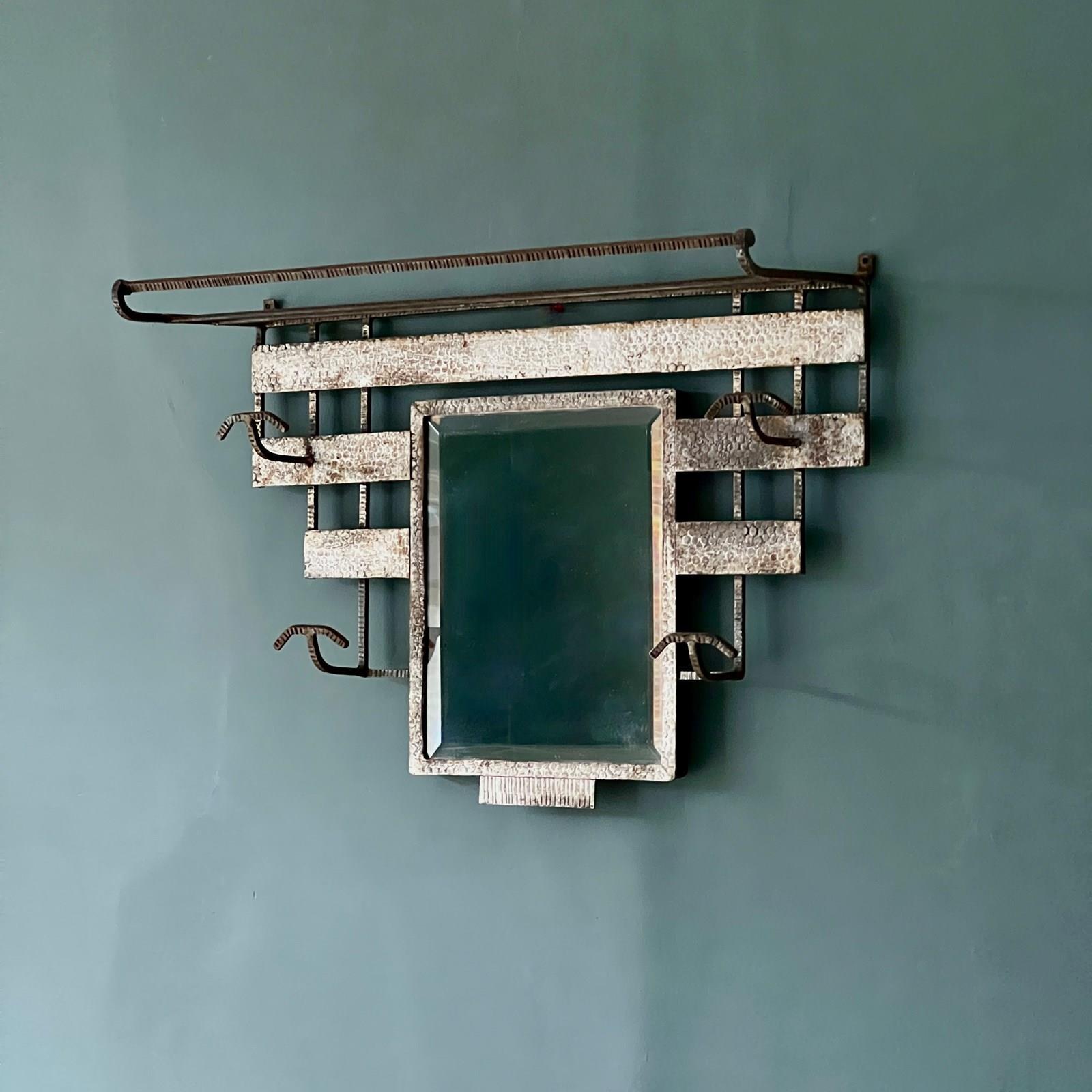 Améliorez votre entrée ou votre salle de bain avec ce miroir porte-manteau et porte-bagages Art déco polyvalent et élégant. Fabriquée en fer forgé à la main, cette pièce comporte une crémaillère en forme de volute avec des encoches, quatre crochets