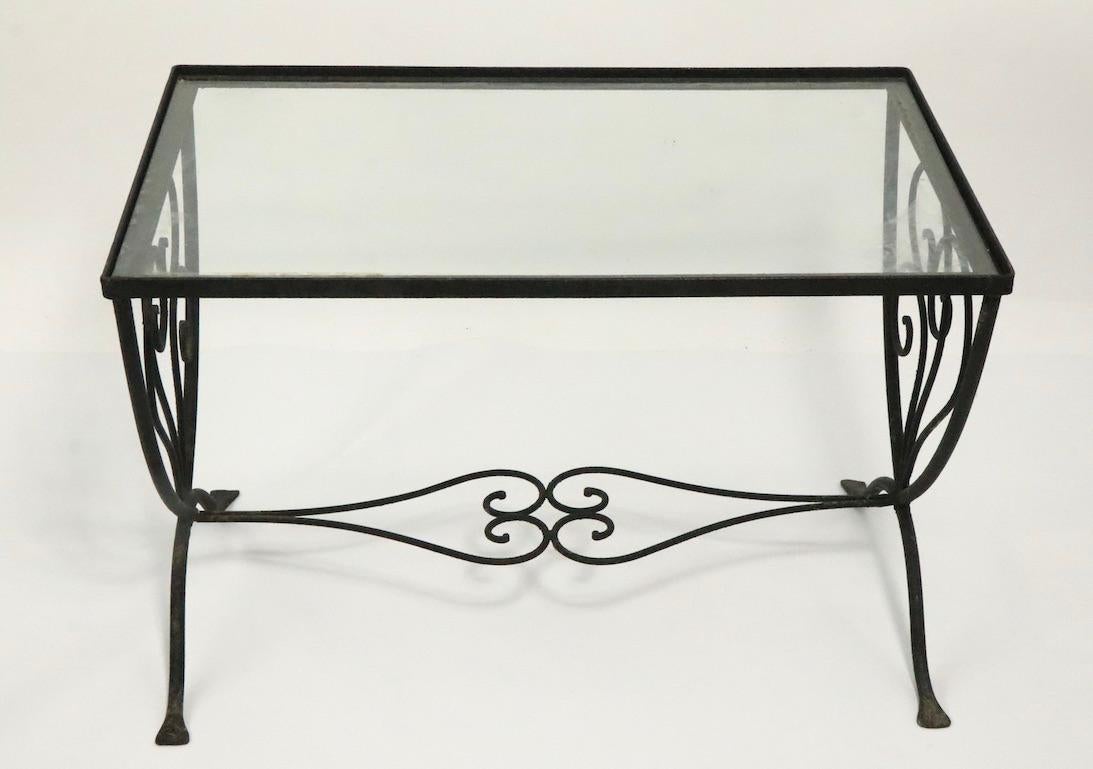 Elegant and stylish wrought iron patio, garden side or end table having a handwrought base with original plate glass inster top. The table is good structural condition, free of bends, breaks, or repairs, the surface is original, and shows the