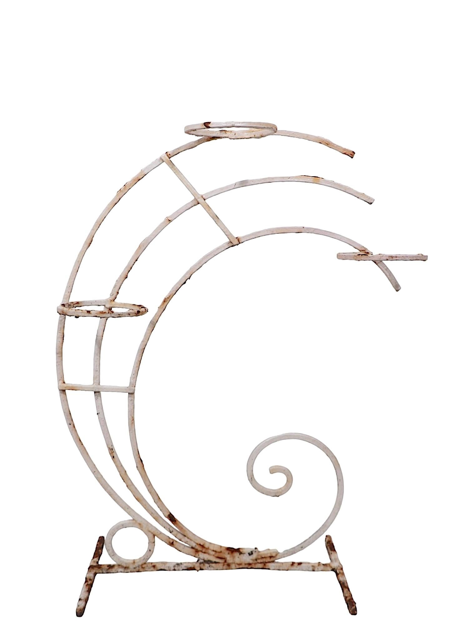 Un portapiante Art Deco elegante e sofisticato con tre portavasi ad anello ( 5in. Dia ) sostenuta da tre archi curvi semicircolari, montati su una base a forma di H. H. Questo esemplare è strutturalmente sano e robusto, la finitura presenta usura