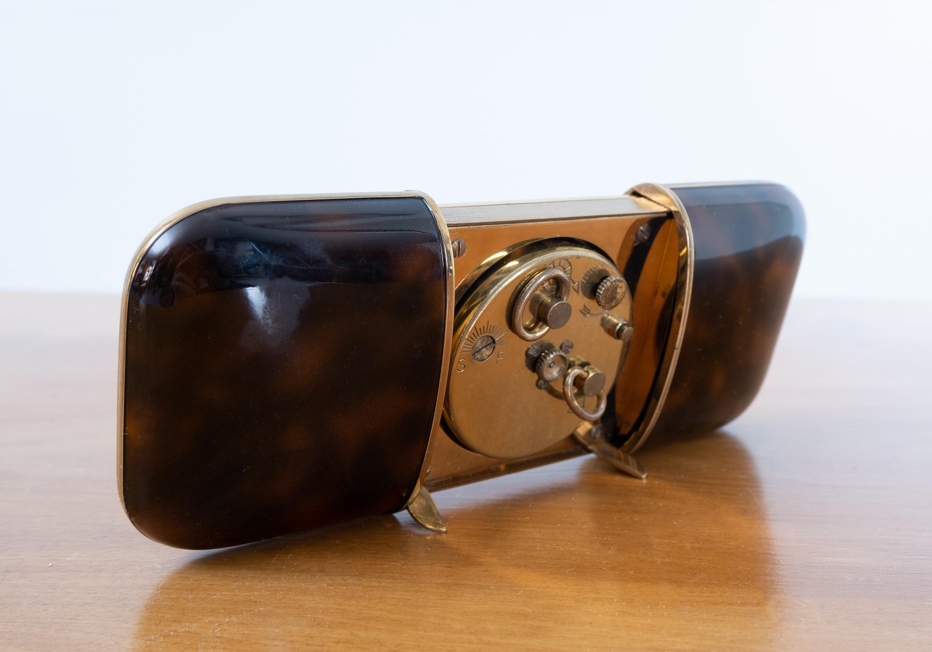 Art Deco Wuba Germany traveling or desk clock. Faux turtle shell case, comes with nice brass
details. When slide open automatically its little standards click out. One-day clockwork. Alarm clock everything in good working condition.
Lovely and