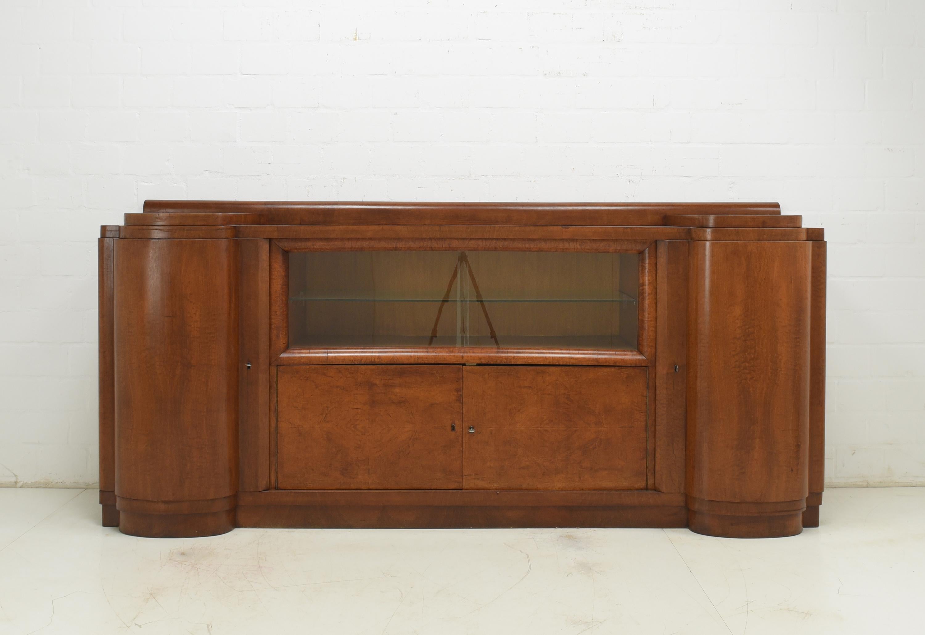 XXL sideboard restored Art Deco around 1930 walnut showcase large

Features:
Tiered, four-door model with sliding glass doors and interior drawers
High quality
Great art deco design
Beautiful patina and grain
Original rod locks
Exceptional,
