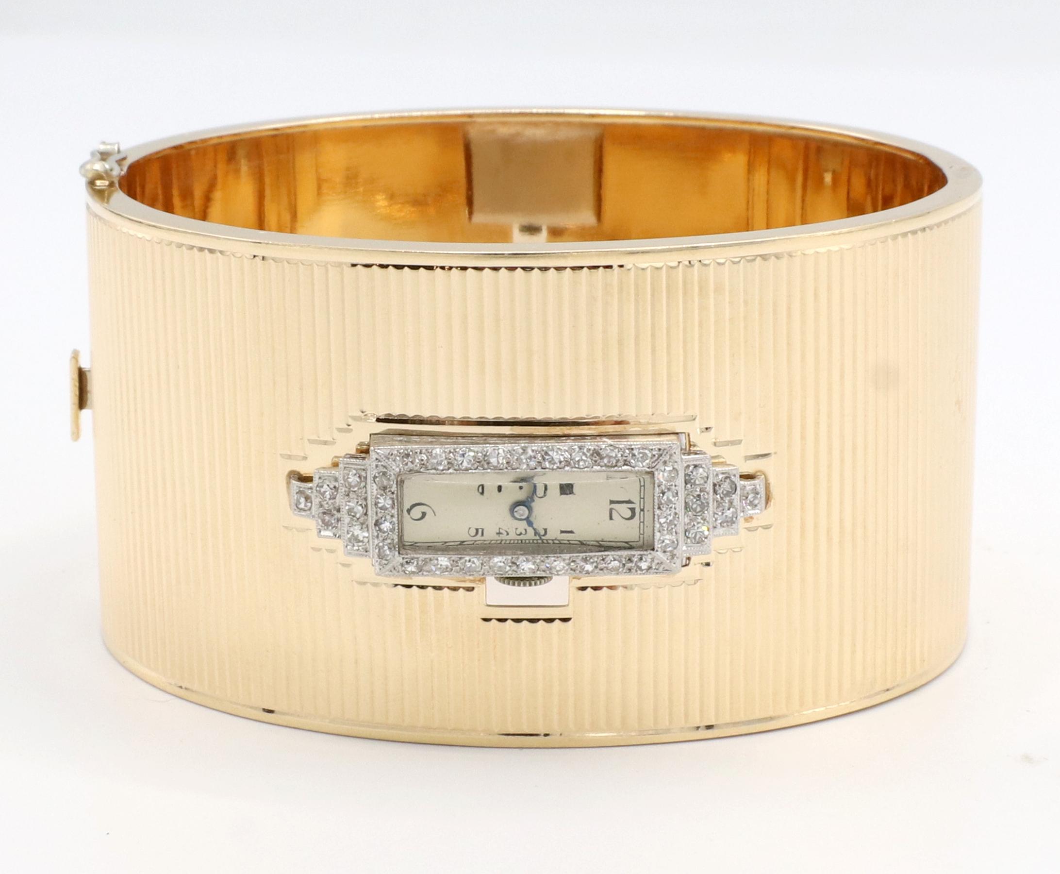 Art Deco Gelbgold & Platin Diamond Hinged Watch Bangle Armband *Uhr läuft nicht*
Metall: 14k Gelbgold und Platin
Gewicht: 72 Gramm
Diamanten: Ca. .75 CTW G-H VS-SI runde Diamanten im Einzelschliff
Breite: 38 mm
Durchmesser: 69 mm
Umfang: Ca. 8