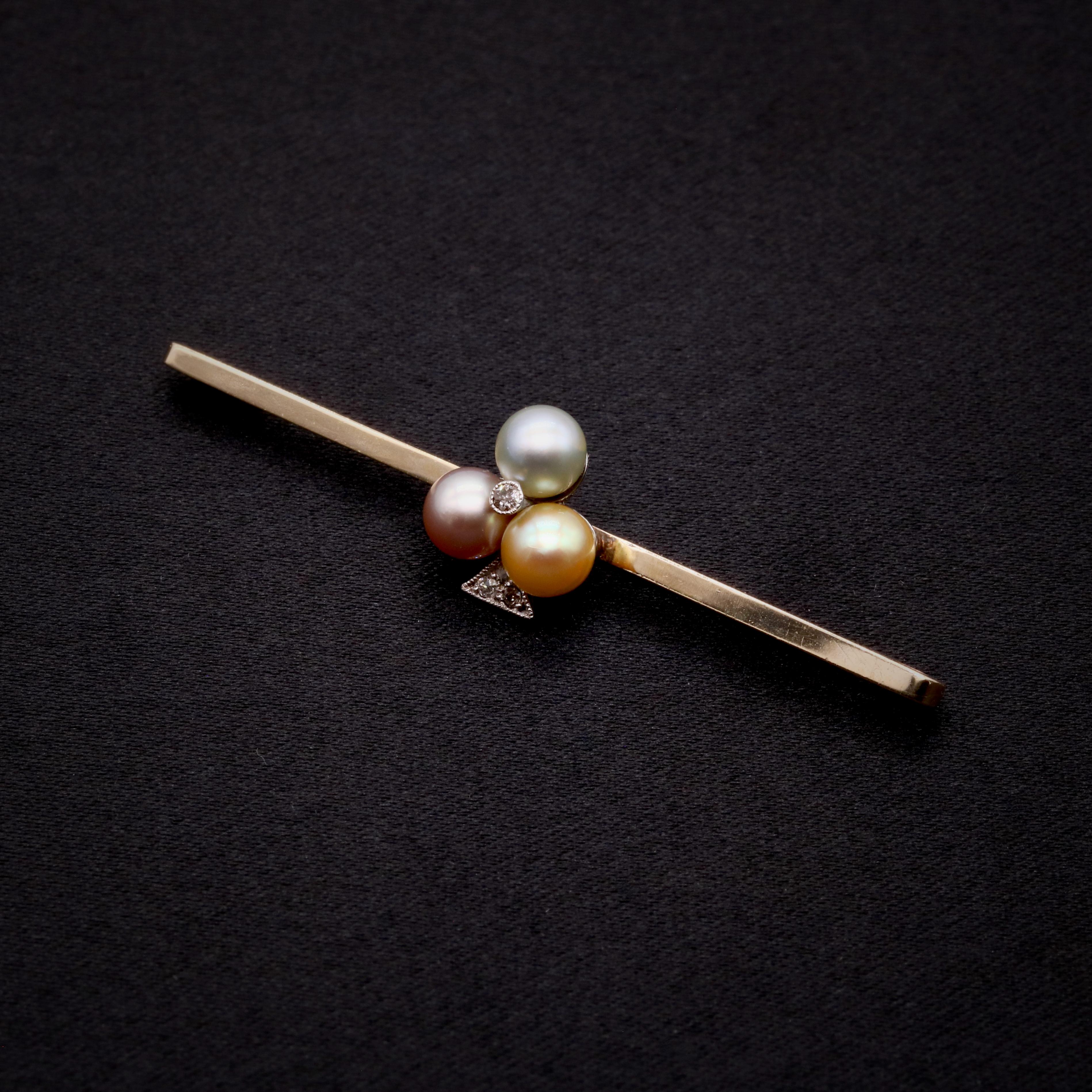 An Art Deco and later pearl, diamond, platinum and yellow gold brooch, comprising three round pearls of different hues, and four old single cut diamonds, set in platinum, to a 9 karat yellow gold bar brooch, with 9 karat yellow gold pin and