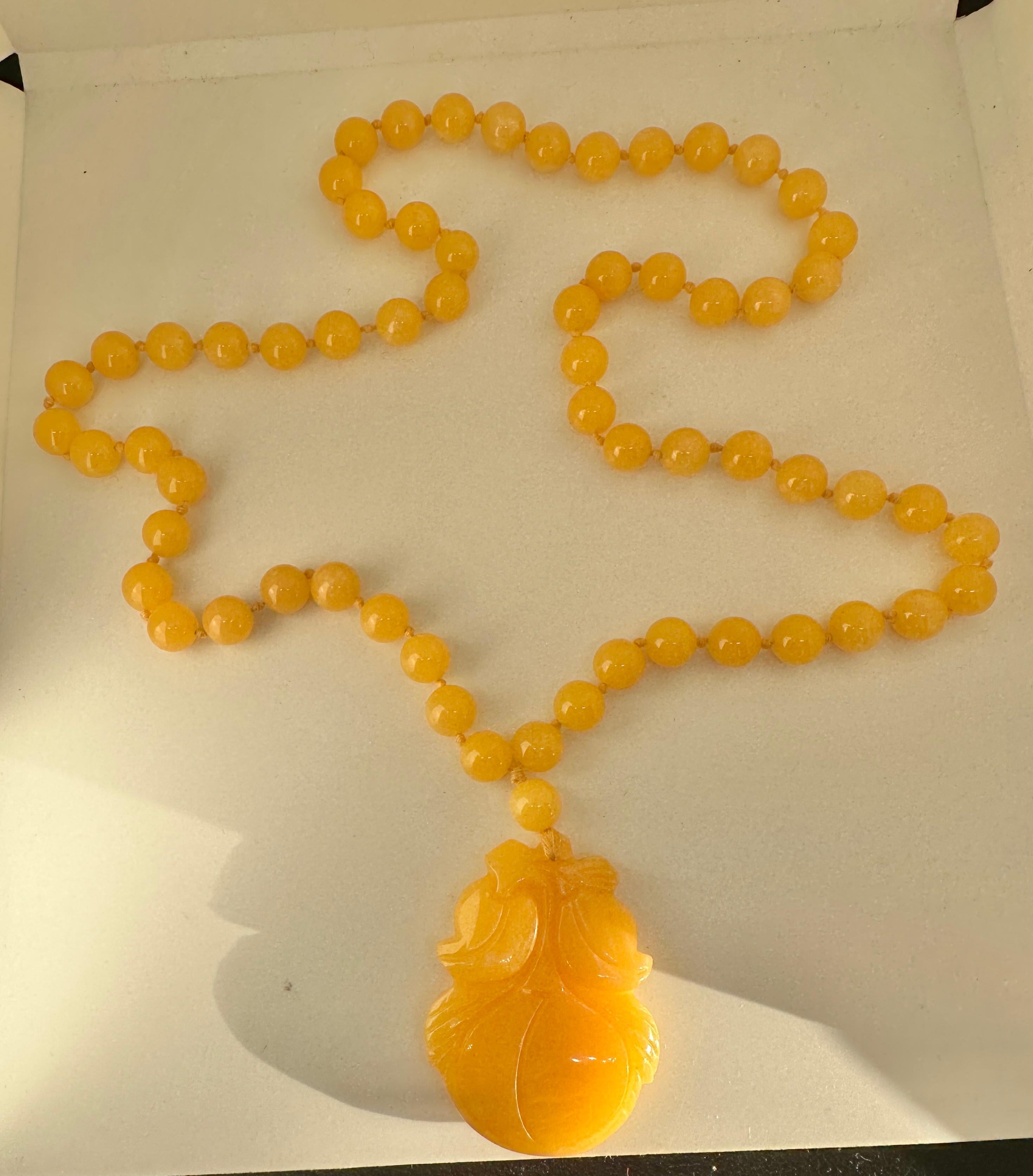 THIS IS AN EXQUISITE AND RARE ART DECO YELLOW JADE AND CARVED FRUIT MOTIF PENDANT NECKLACE OF 29 INCHES IN LENGTH.  THE STUNNING NECKLACE HAS GORGEOUS 10MM YELLOW JADE BEADS.  EACH BEAD IS INDIVIDUALLY KNOTTED.  THE QUALITY AND COLOR OF THE YELLOW