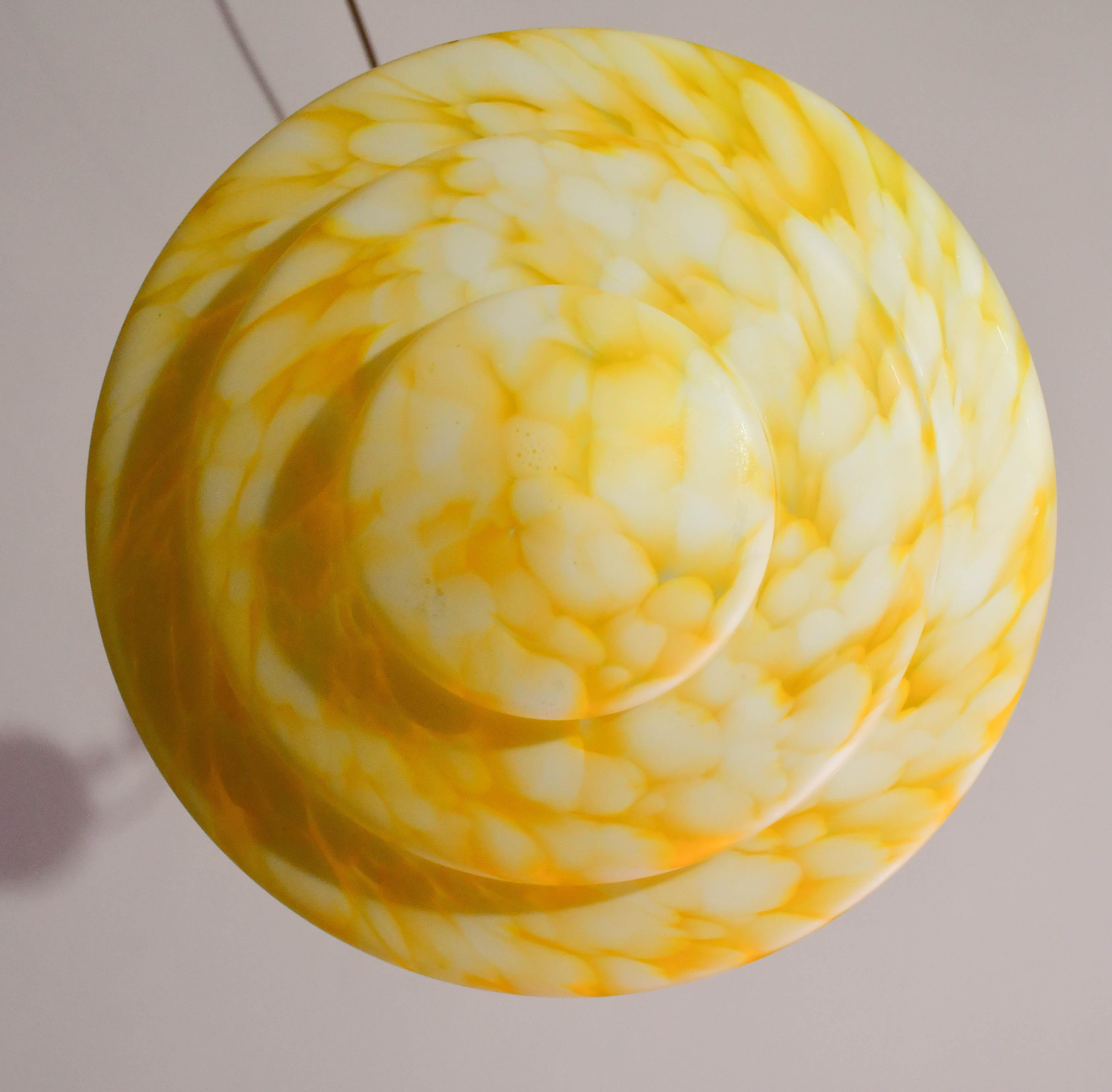 Superbe pendentif en verre de Murano de couleur jaune.

Style Art déco : période de fabrication 1960-1970.

Le disque du lustre est de couleur jaune avec des reflets blancs suspendus aux trois cordes d'origine.

Une lampe e27.

Diamètre du disque 32