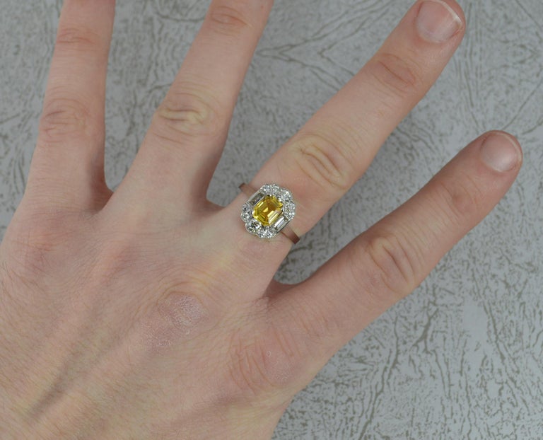 A stunning quality Yellow Sapphire and Diamond ring in Platinum.
​Designed with a large emerald cut vivid yellow sapphire to the centre in four claw setting. 5.4mm x 6.5mm approx.
Surrounding are ten round brilliant cut natural diamonds and two