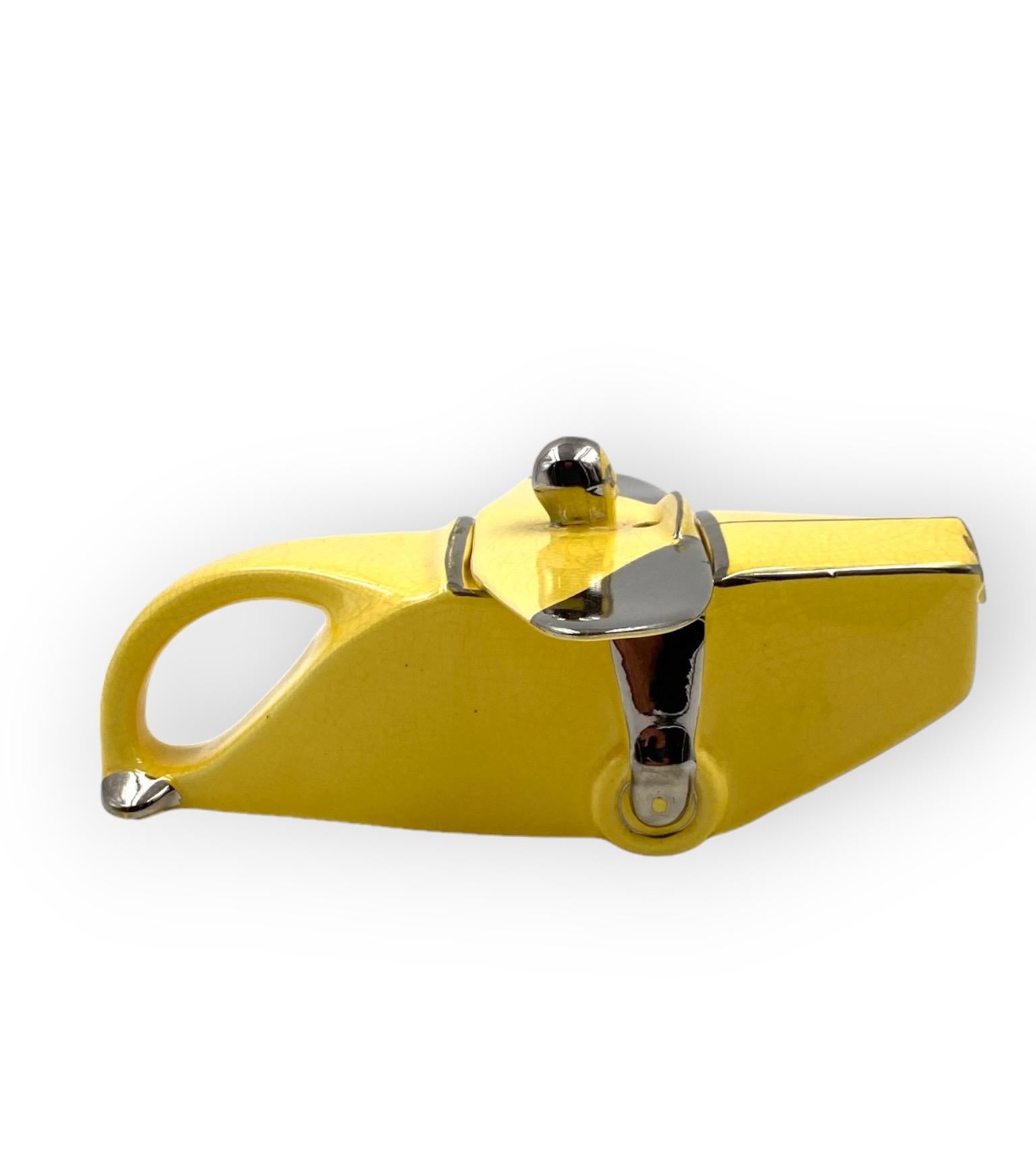 A rare Art Deco 'T-Plane' airplane teapot

Sadler, UK, 1930s. First edition

ceramic in custard yellow glaze with chrome lustre detailing, with 'Old bill pilot and wings' lid.

H 10.5 cm - 23 x 22 cm

Conditions: excellent, no dents or chips.