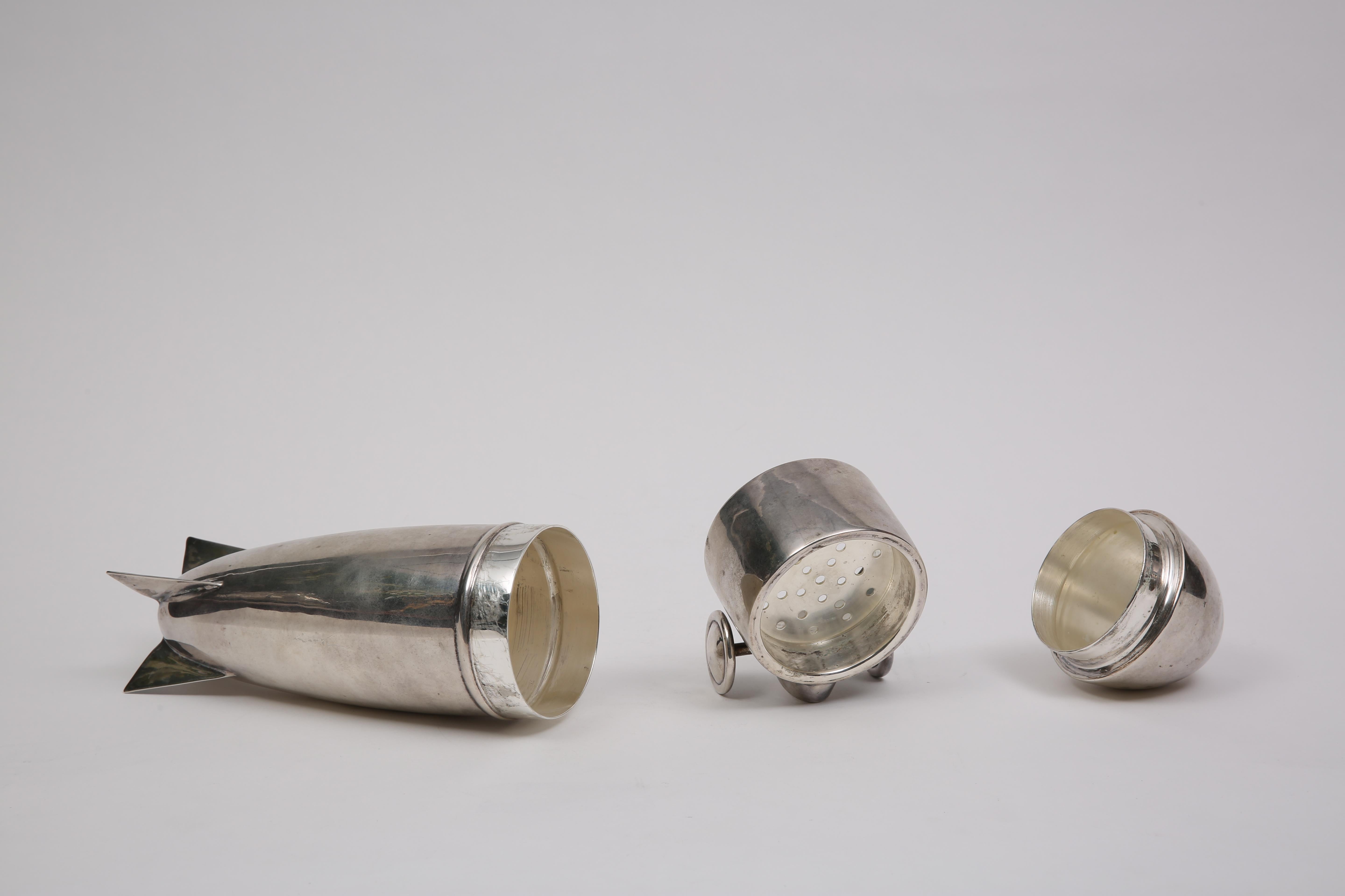 This piece was designed to be a traveling cocktail bar in the shape of the Zeppelin Airship. It is very rare and in pristine condition. Its silver plated brass in material and has an integral strainer with a removable lid, and cap. This piece is