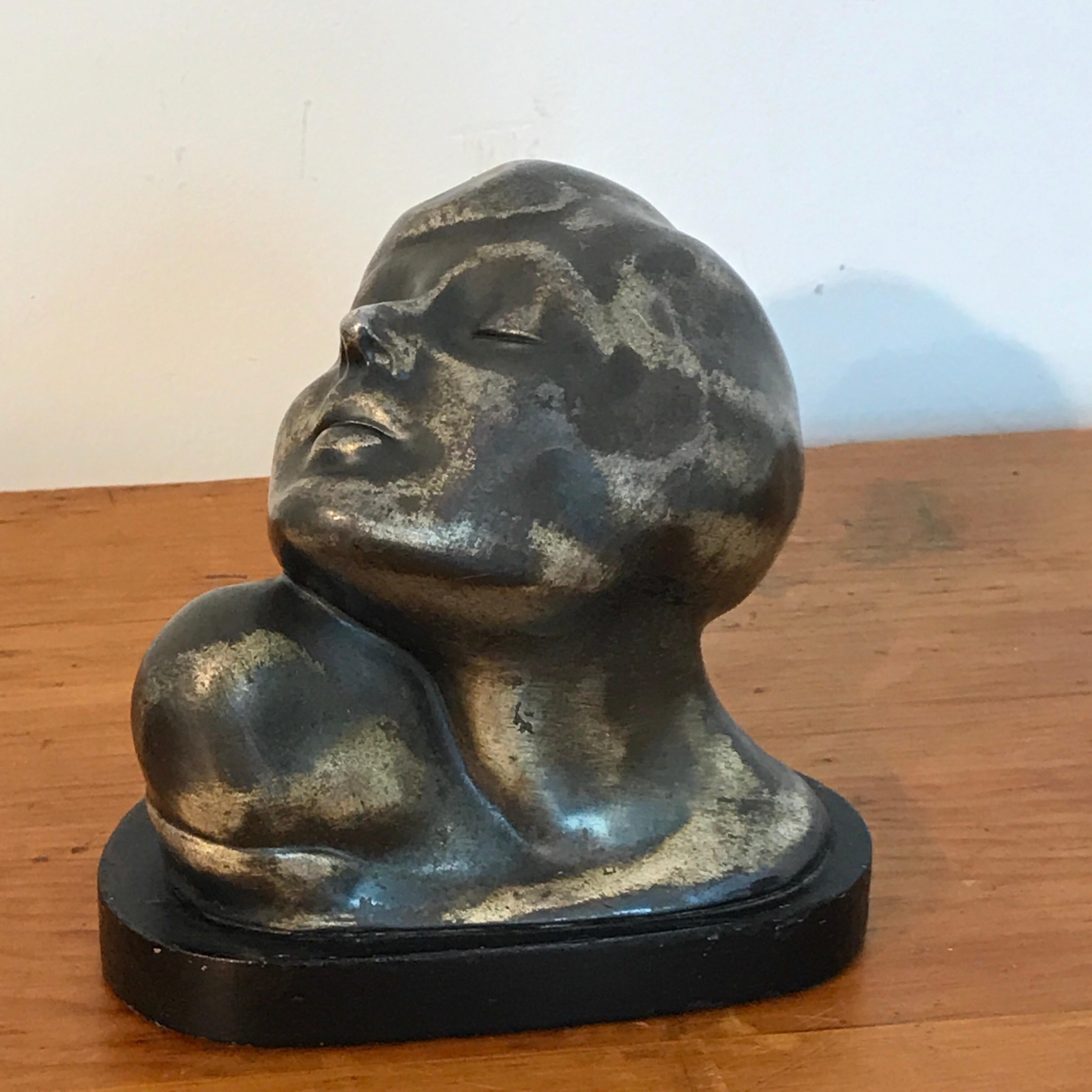 Art Deco zinc flapper portrait bust, with her head tilted wearing a bobbed haircut, raised on a ebonized wood plinth base.
 
