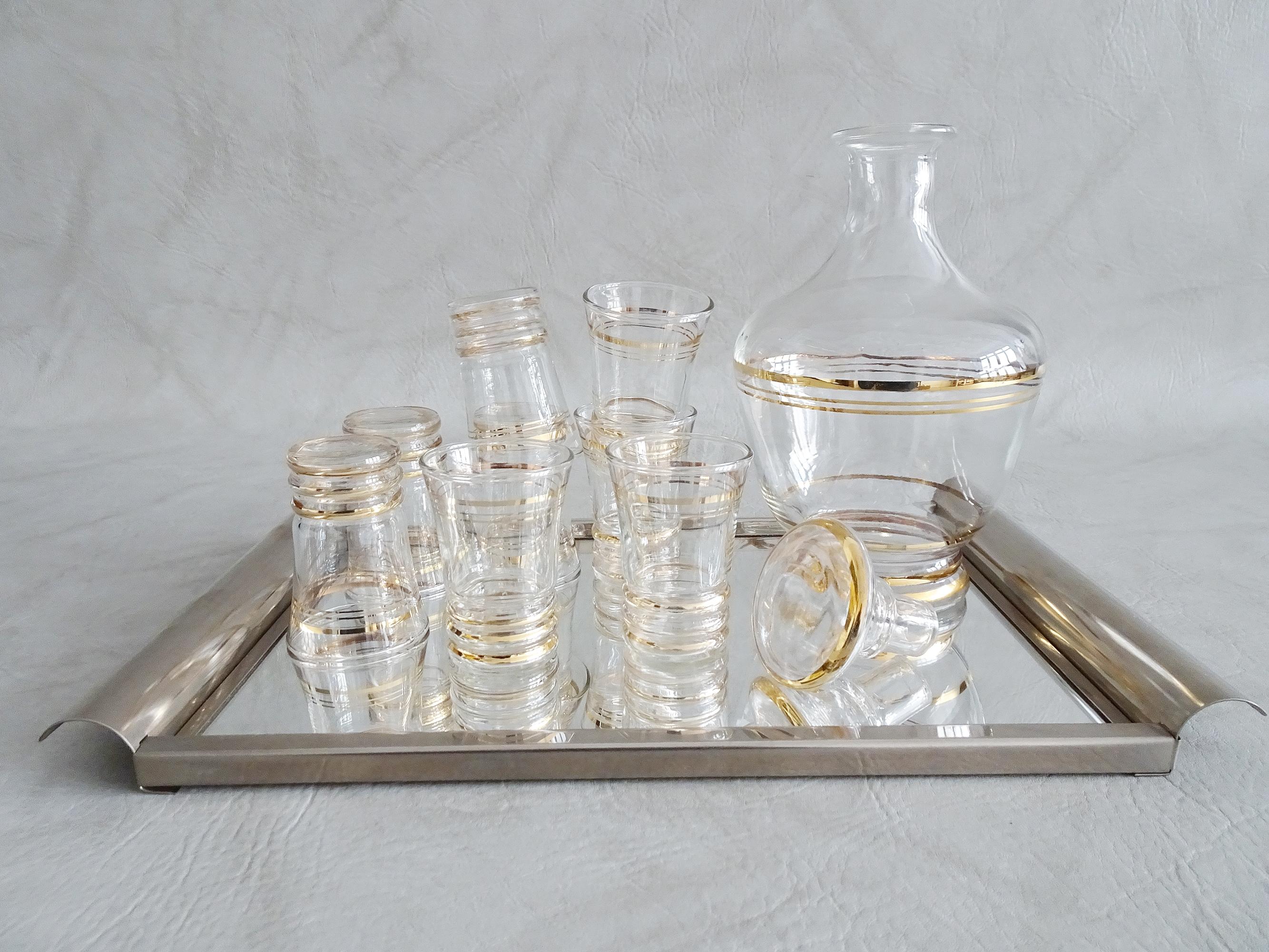 Stylish bar set consisting of a liqueur carafe with eight glasses and a tray. A fancy bar accessory that impresses with its color and design. Glass carafe in gold-colored stripes with the matching shot glasses. The rectangular tray has a surface