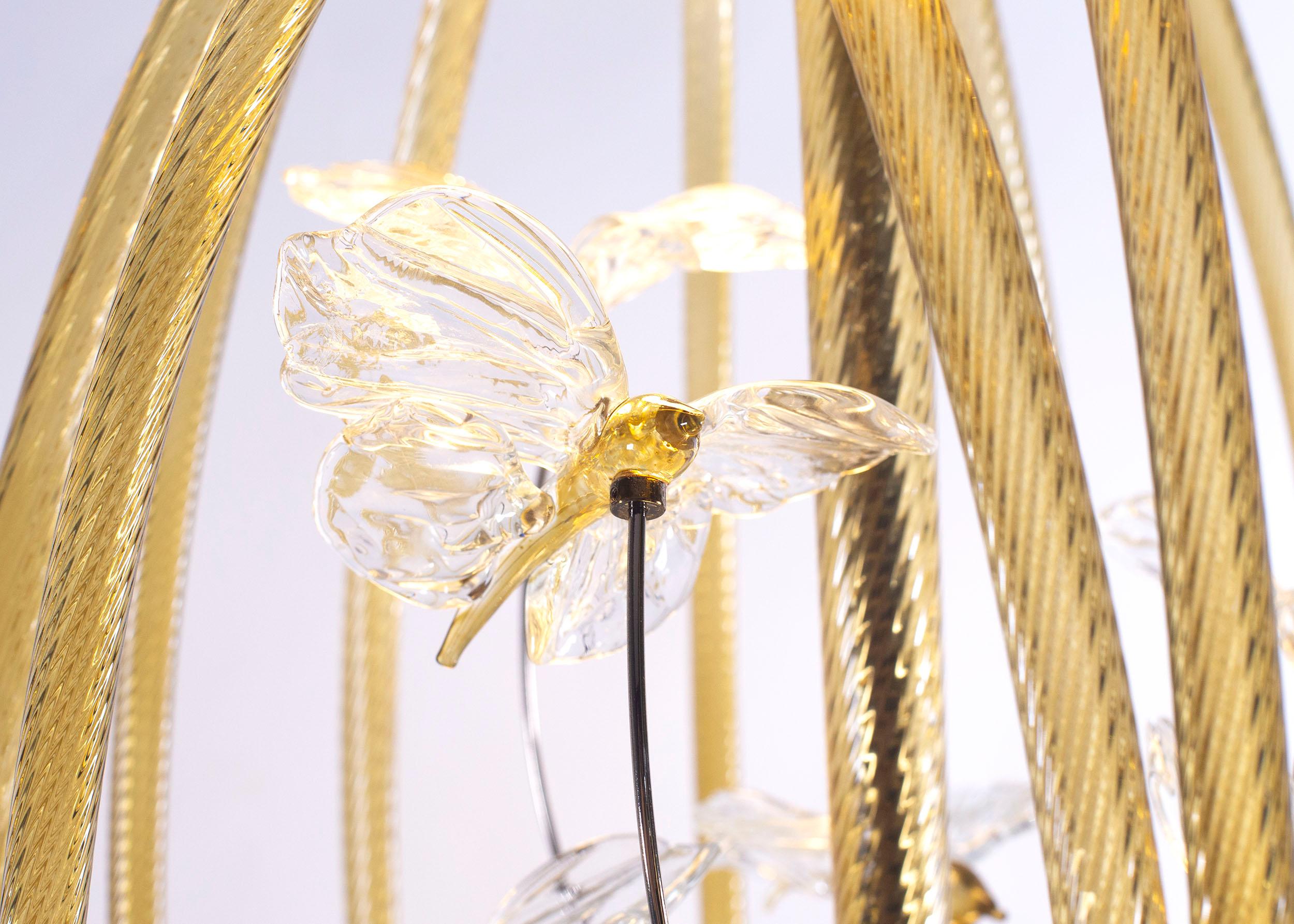 Lampada da terra artistica Cage in vetro color paglia di Multiforme con farfalle modellate a mano da maestri vetrai. Un oggetto che combina il savoir-faire artistico di Murano con i dettagli tecnici del componente di illuminazione.

L'estetica di un