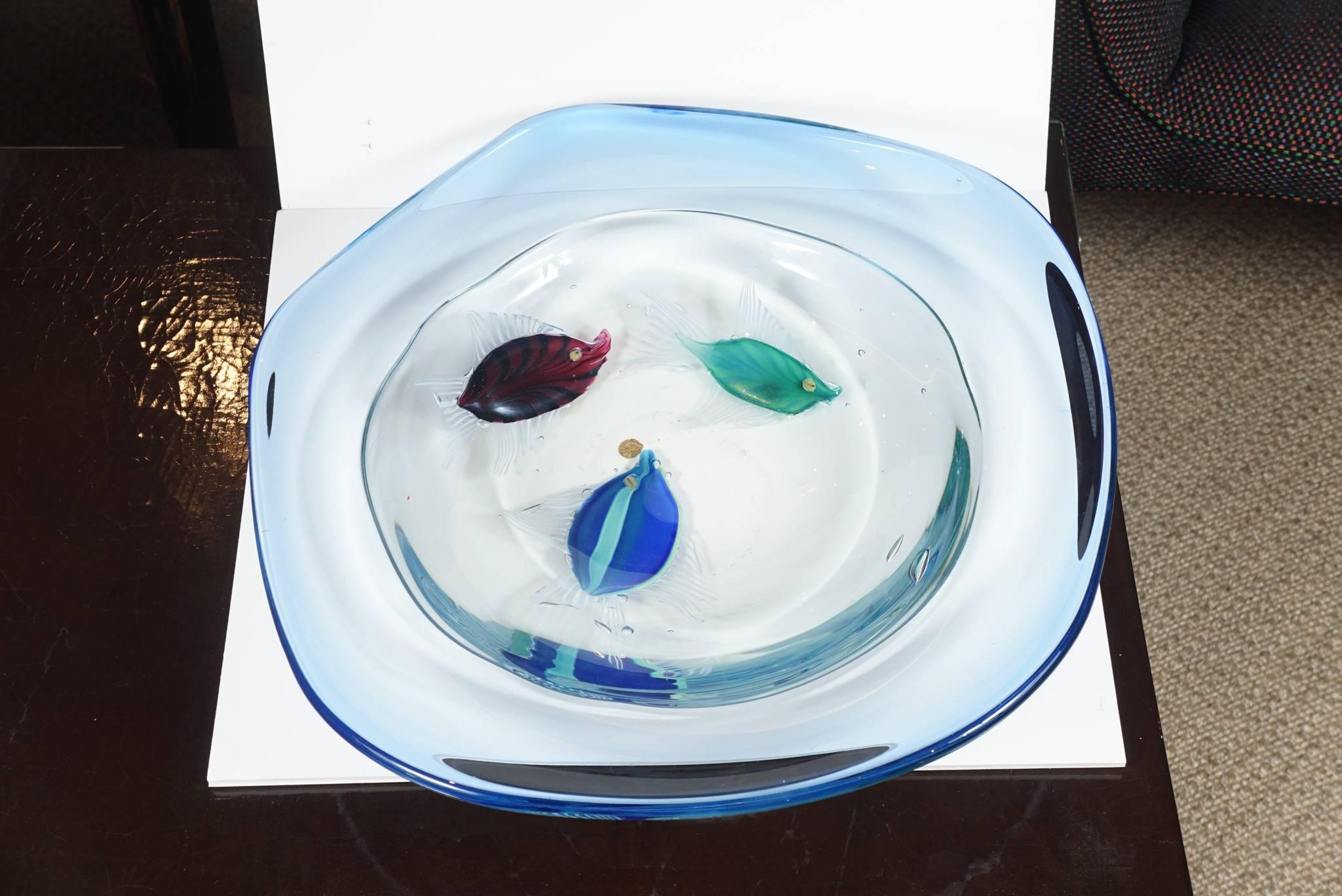 Here is a unique art glass bowl with three fish in a clear to cobalt blue color. The large bowl is very heavy and has the sense of a pool of water ranging from a transparent color to a sea blue and a cobalt blue. The piece is signed by the artist