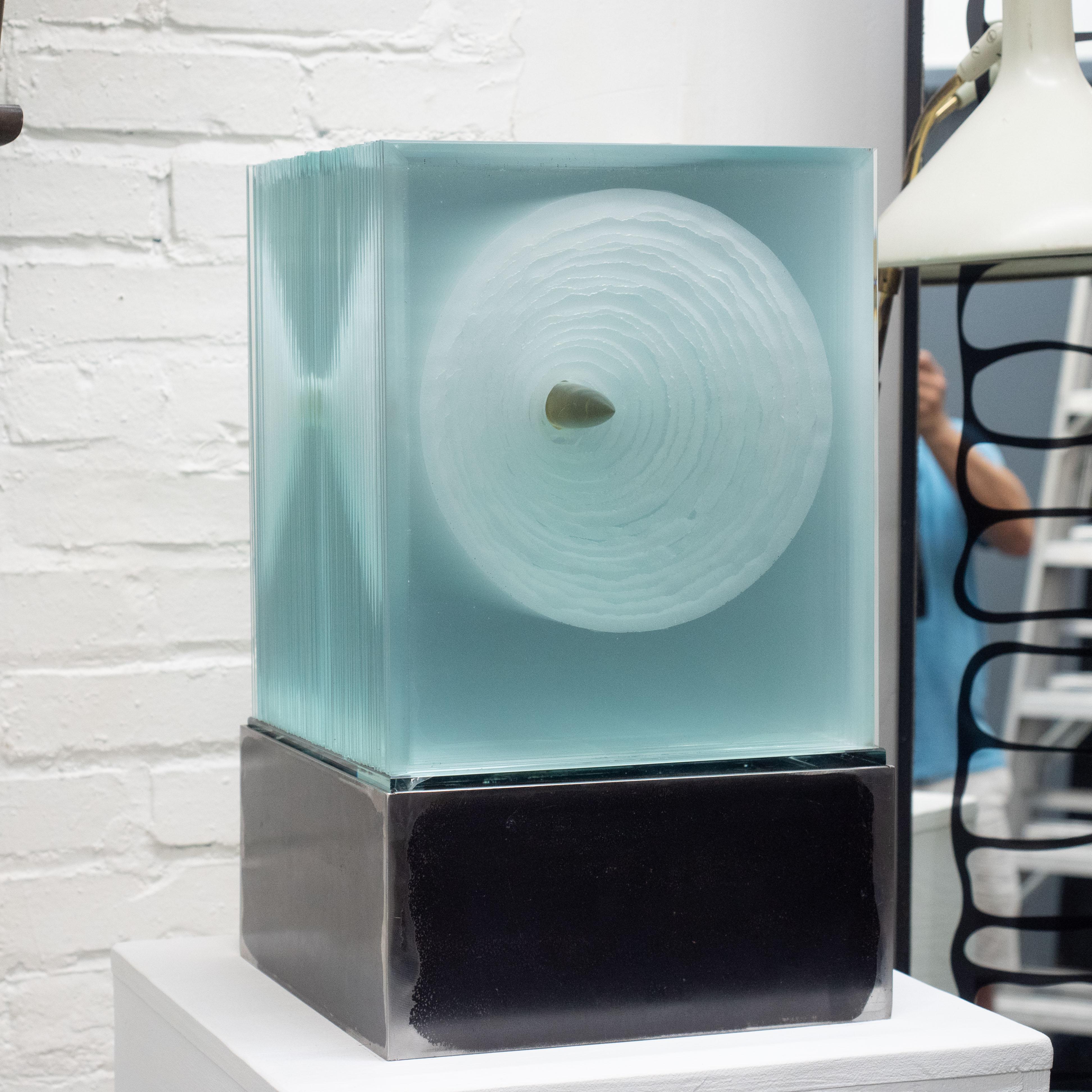 Sculpture cubique en verre sans titre de Jiri Jelinek. Composé de plusieurs dalles de verre compressées avec diverses techniques appliquées pour créer des effets visuels géométriques distincts selon les angles de vue. Éclairage par LED dans une base