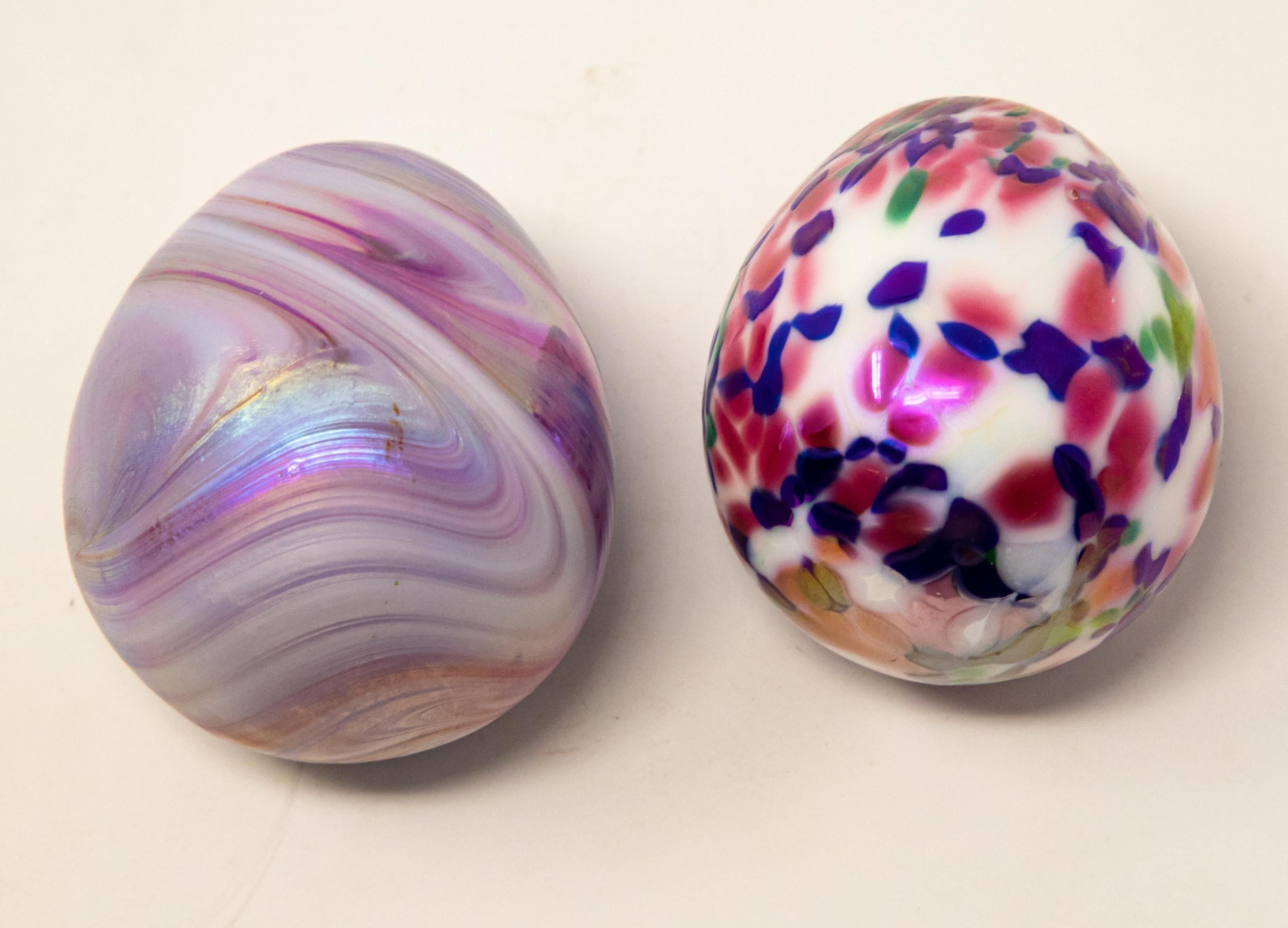 Offering a unique pair of art glass eggs. One is white with blue, green and pink dots, and the other is iridescent in purples and silvers.