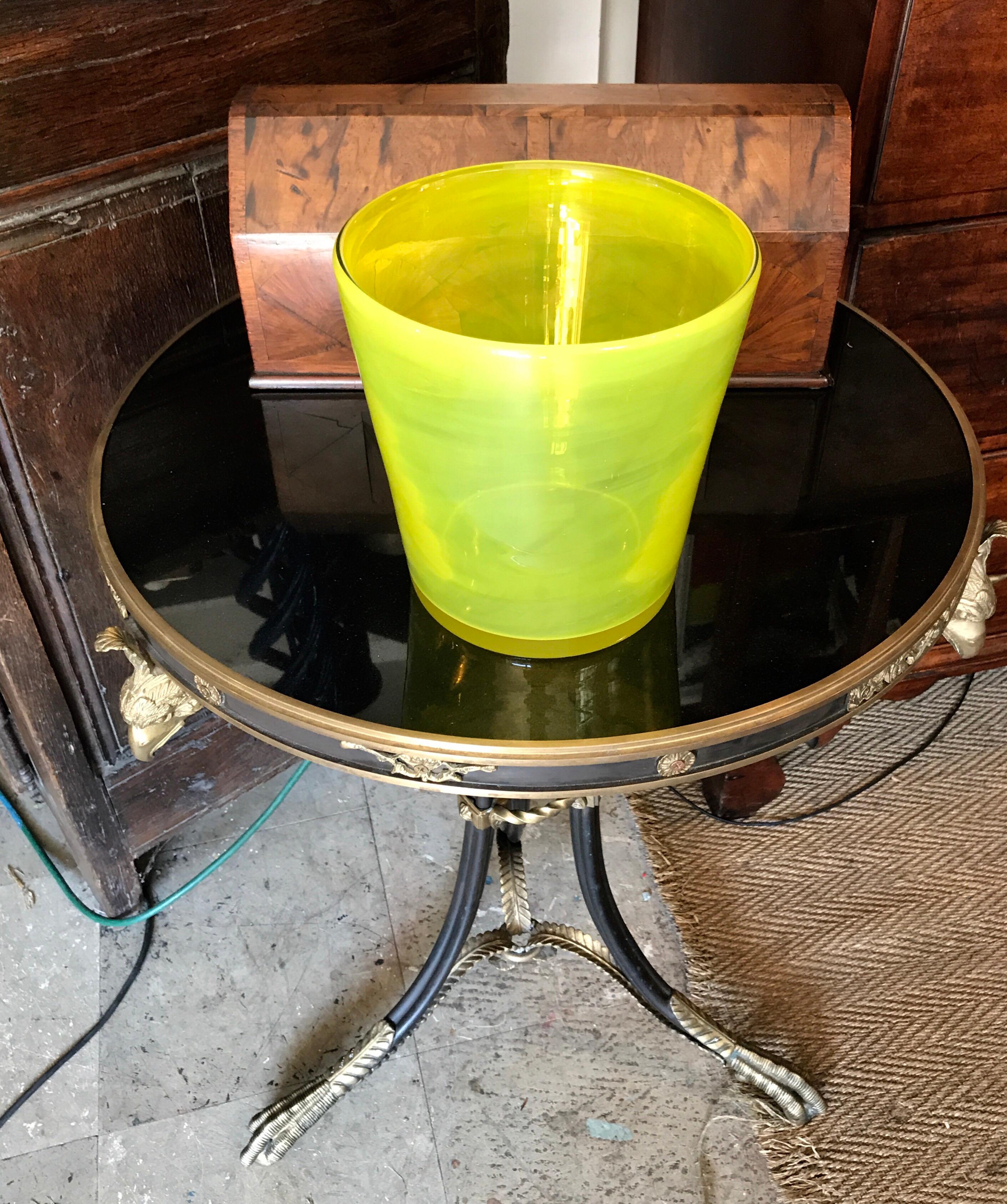 A stunning and eye-catching art glass ice bucket in a vibrant citron yellow or green. The vessel has a soft rounded top edge and slight turning ripples down the face of the wine bottle cooler form. The bottom is smooth, flat and polished, 1980s