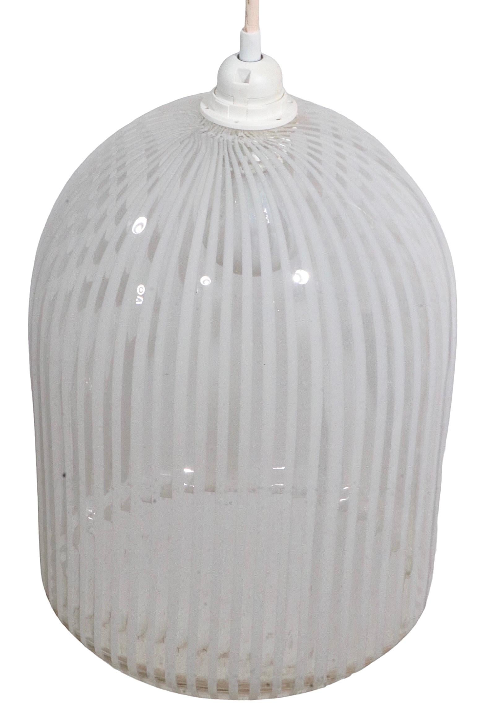 Chic and stylish art glass hanging dome with transparent ground and white stripes. The glass body is dome form, with a large opening on the bottom ( 9.5 in. Dia. ). It accepts a standard size screw in bulb, and is in very good, working condition,