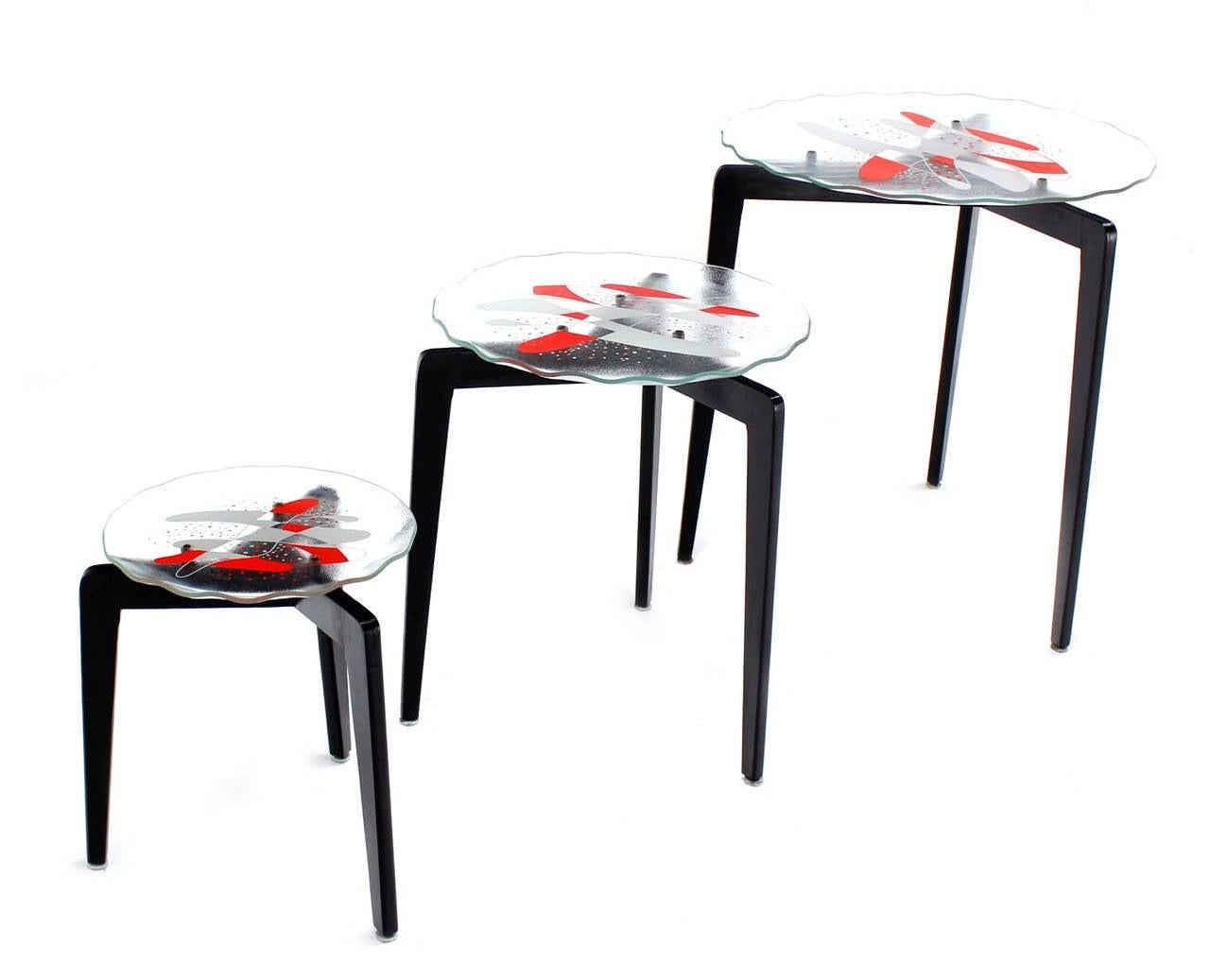 Set of 3 Art glass nesting side occasional side end tables. Nice tapered legs design. Black lacquer finish. Etched glass tops white and red lacquer design pattern.