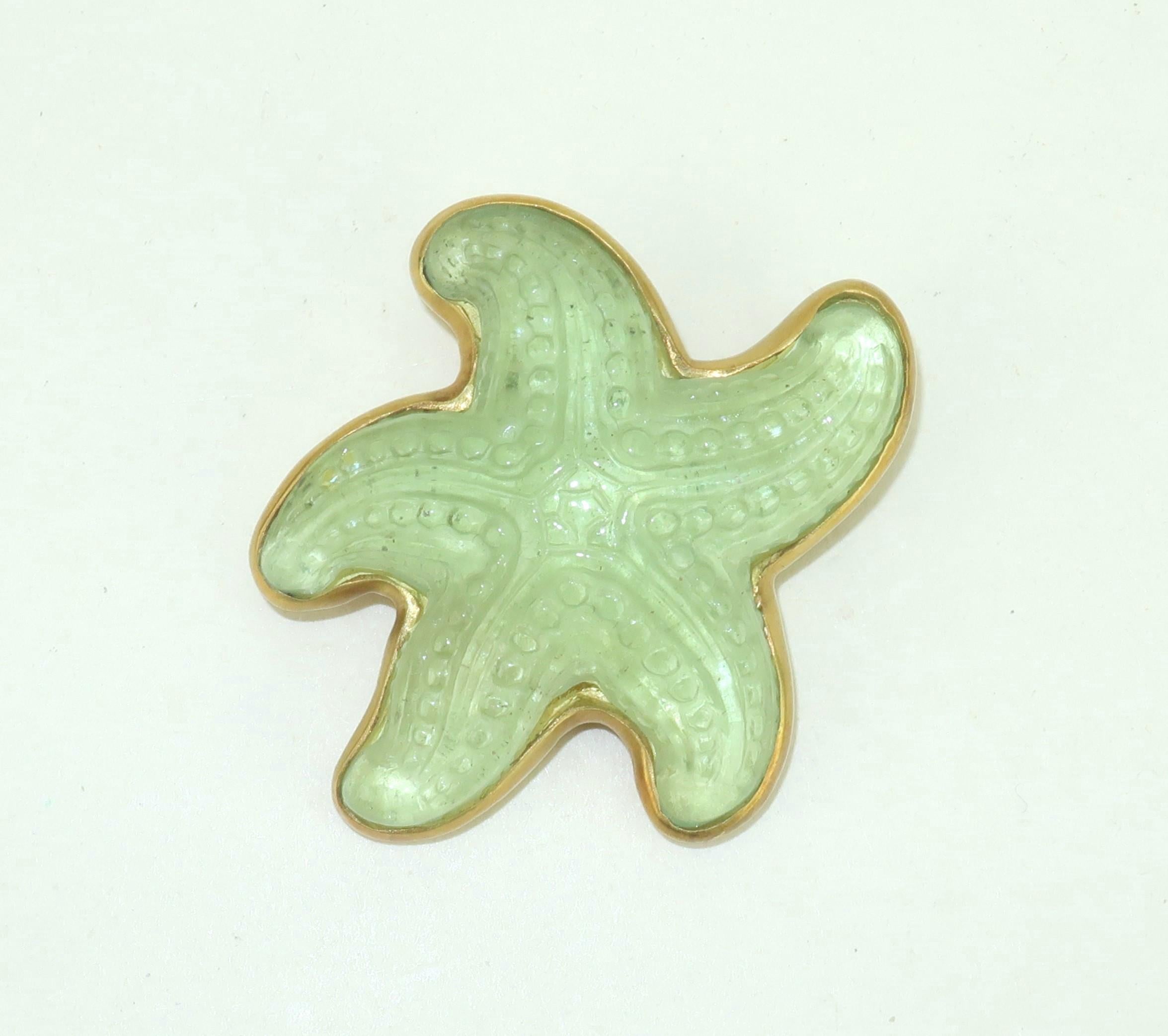 Hübsche Seesternbrosche aus Kunstglas nach Art von Lalique.  Der detaillierte Seestern ist in eine goldfarbene Metallbrosche mit gerader Nadel und Sicherheitsverschluss eingefasst.  Das Glas ist in einem leuchtenden Grünton aus Meeresnebel gehalten.