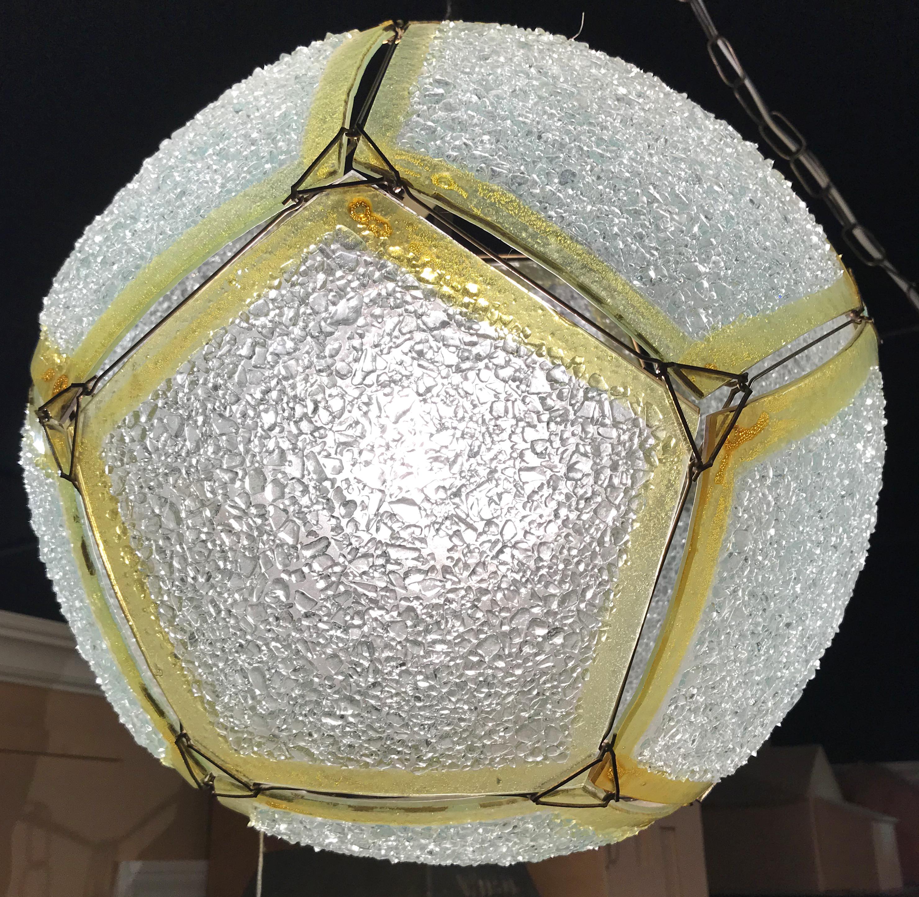 A fabulous art glass textured or frosted sphere pendant light with textured pentagonal panels held together with a series of metal triangular fasteners with metal lines with end hooks running between them. Each pentagonal panel has clear textured