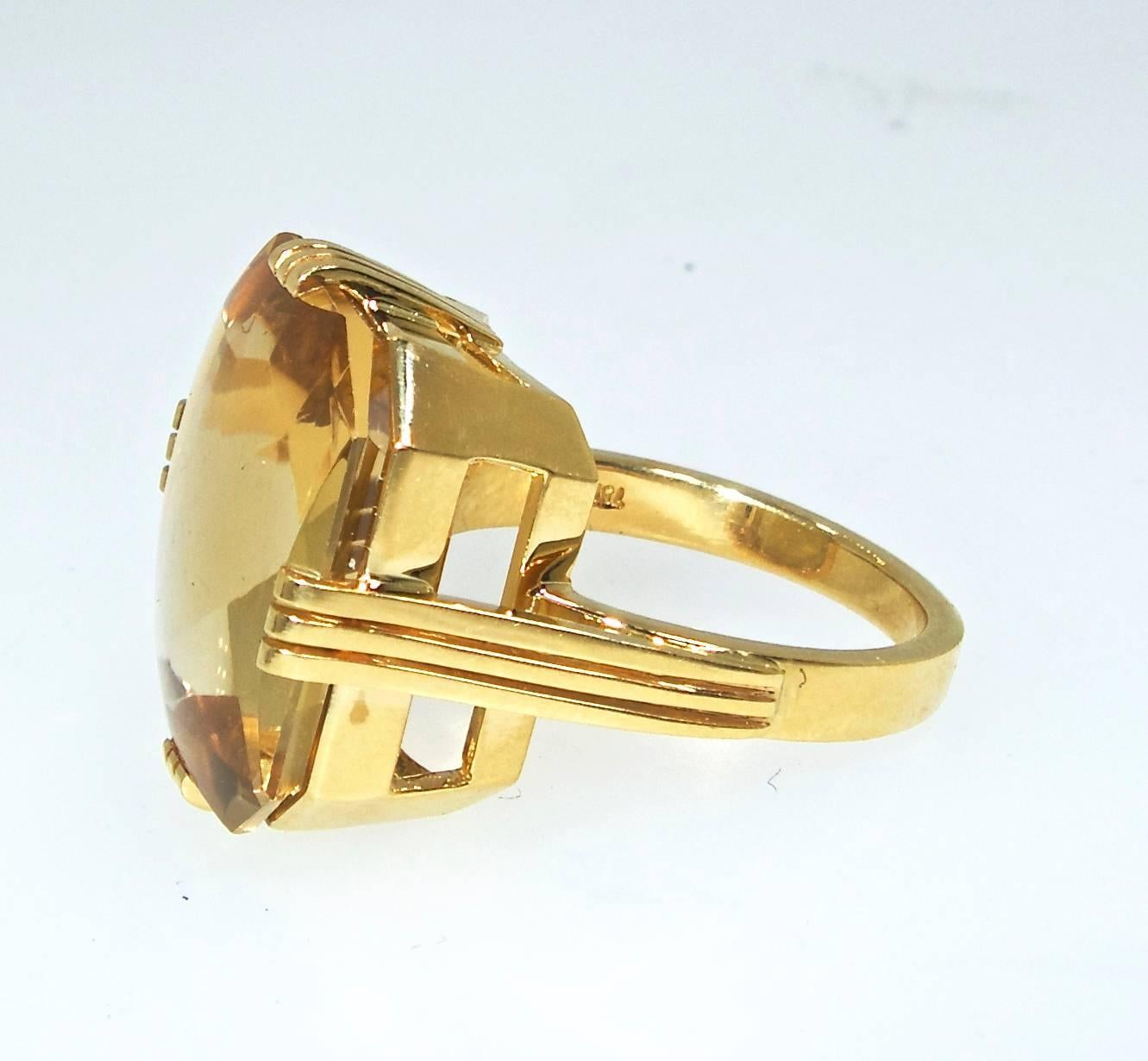 Set in 18K yellow gold the stone weighs approximately 12 cts., this geometric ring was found in absolutely unused condition.  The clipped cornered emerald cut with a buff top and a facetted bottom sits in a mounting of chiseled precision. The