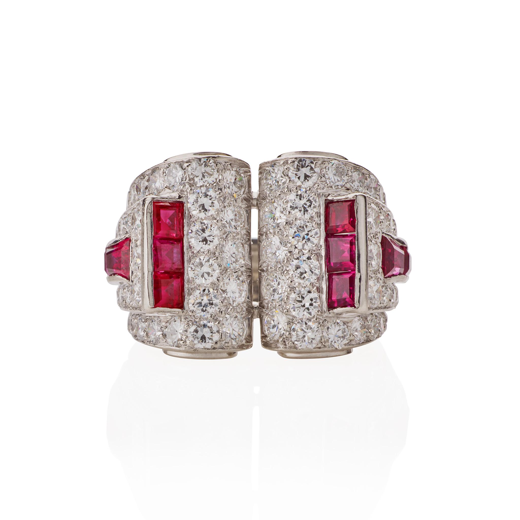 Dieser in den 1930er Jahren entstandene Art-Modern-Rubin- und Diamantring ist in Platin gefasst. Er ist in Form von zwei großen, mit Diamanten besetzten Schnecken mit abgestuften Rändern gestaltet, die mit Linien von Rubinen im Kaliberschliff